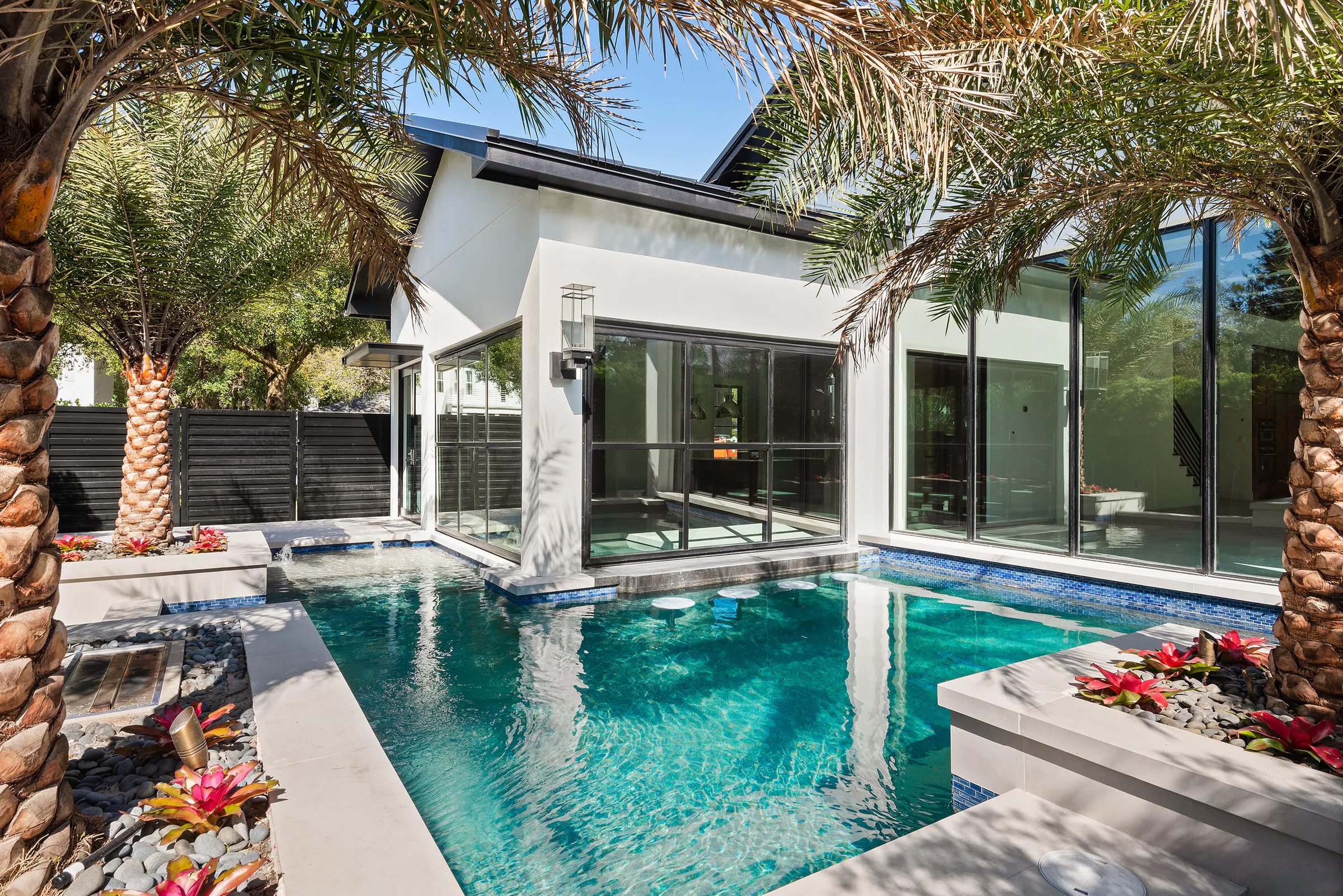 Angled view across the pool toward black-framed garden doors.
