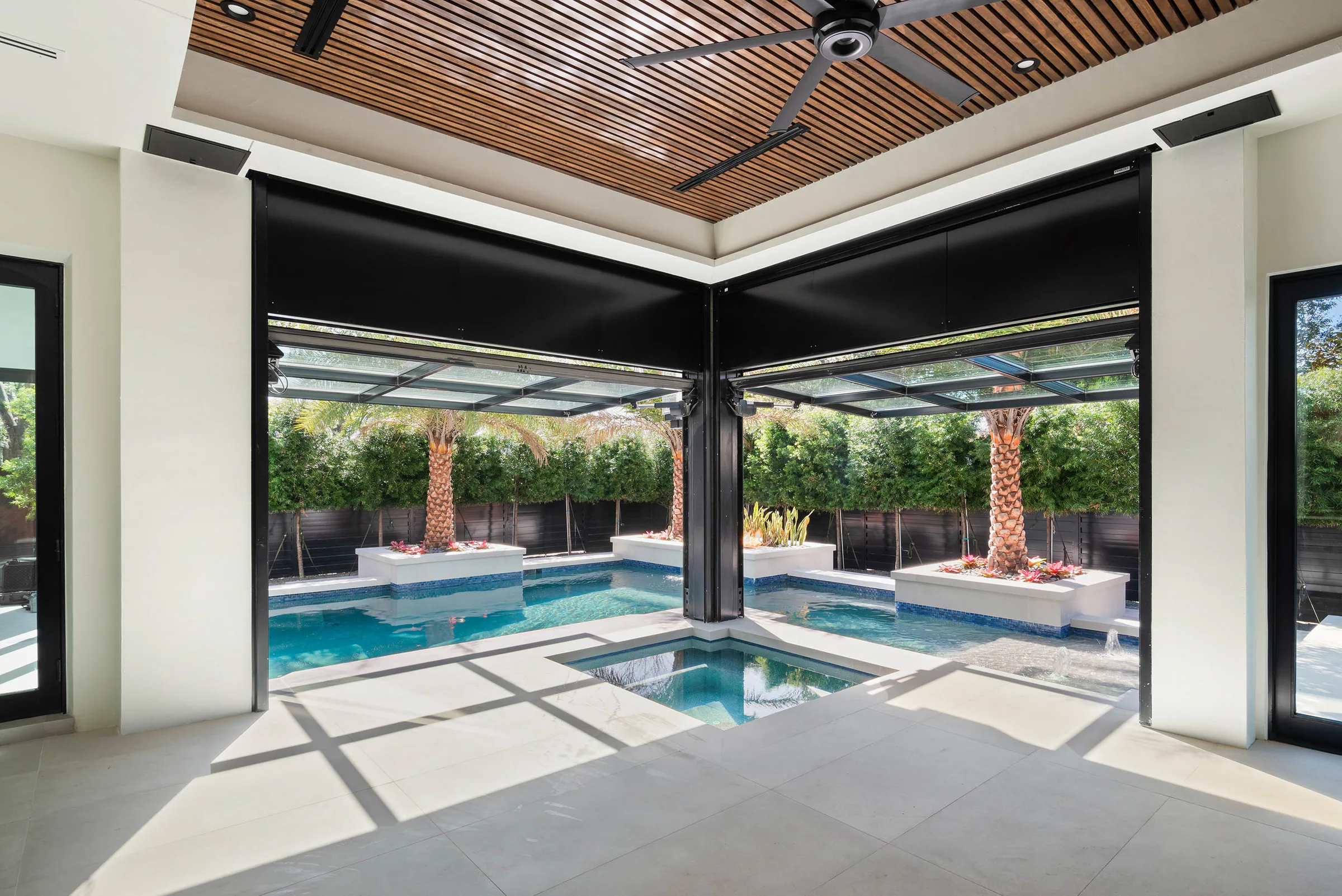 Covered outdoor room with a wood ceiling and pool beyond. Oakwood, a custom home by Rare Builders in Orlando.