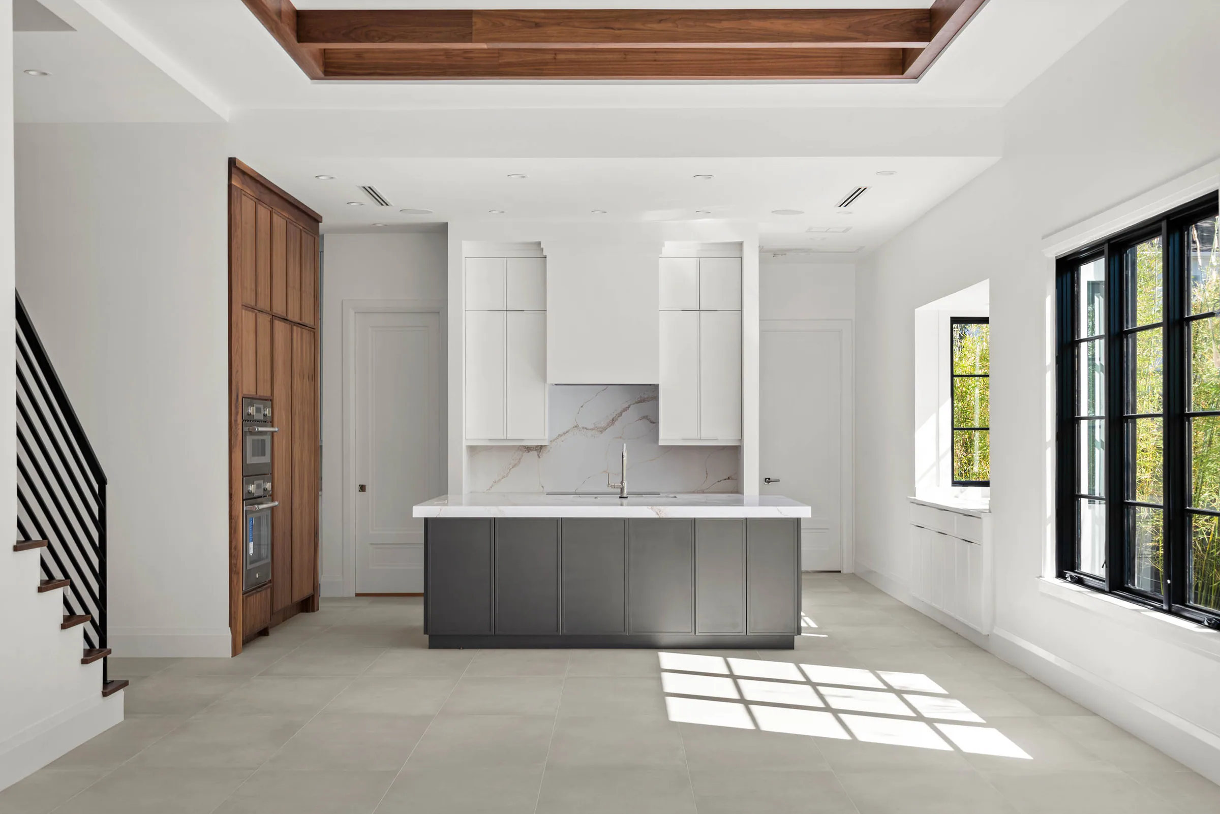 Unfurnished kitchen with a grey island and tall wood cabinetry.