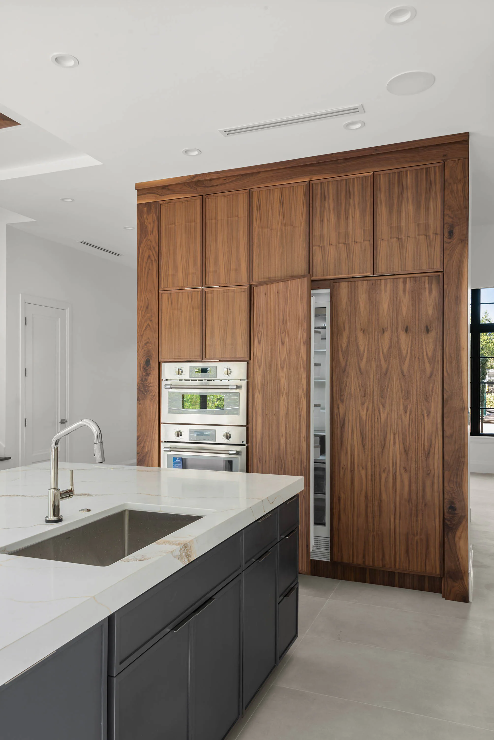 Vertical view of the kitchen island and wood cabinetry. Oakwood, a custom home by Rare Builders in Orlando.
