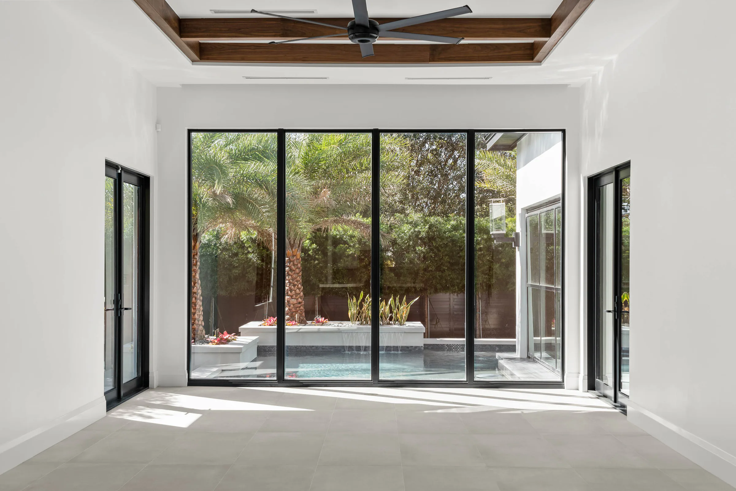 Unfurnished room with broad black-framed doors to the pool.