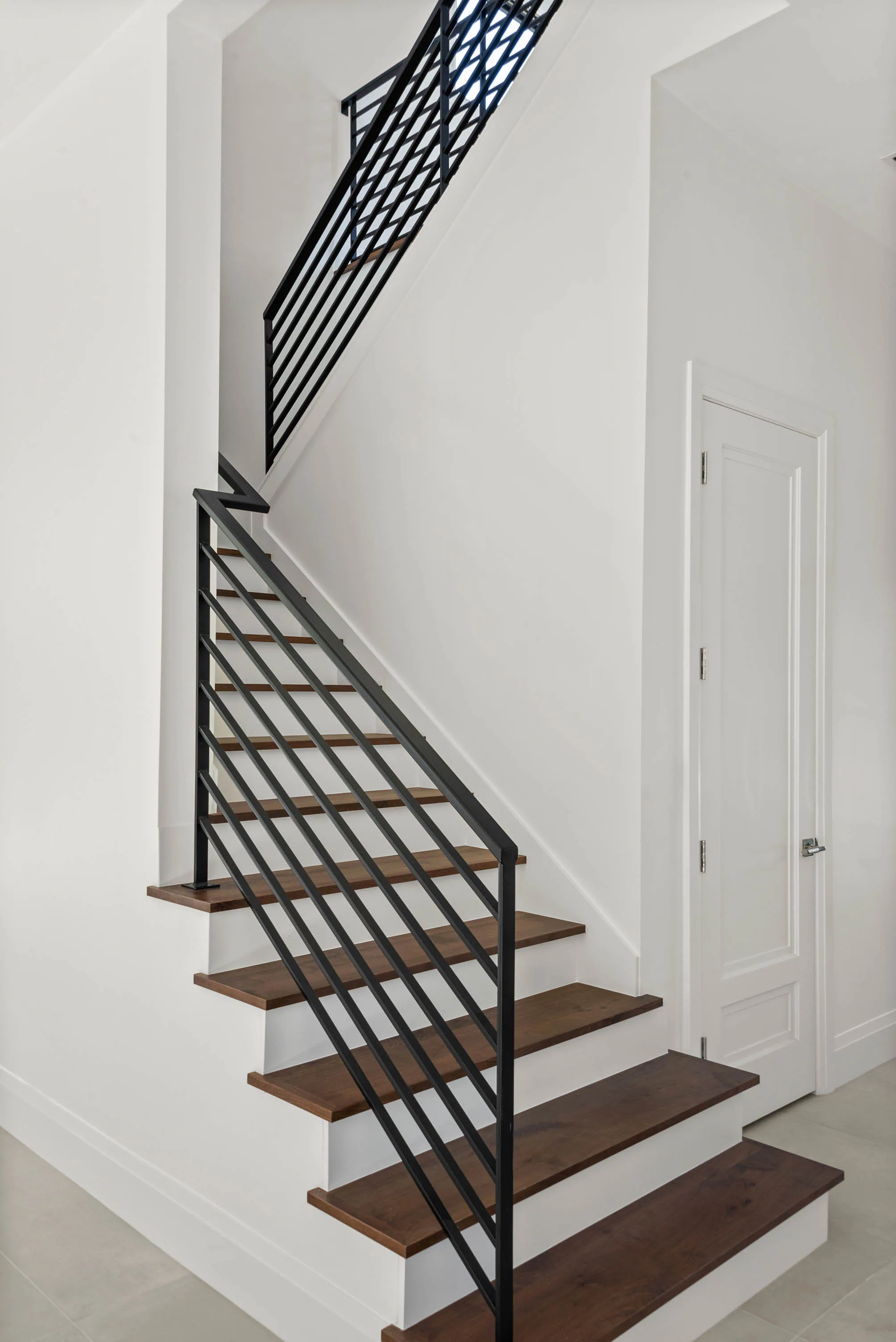 Floating wood stair with a black metal railing.
