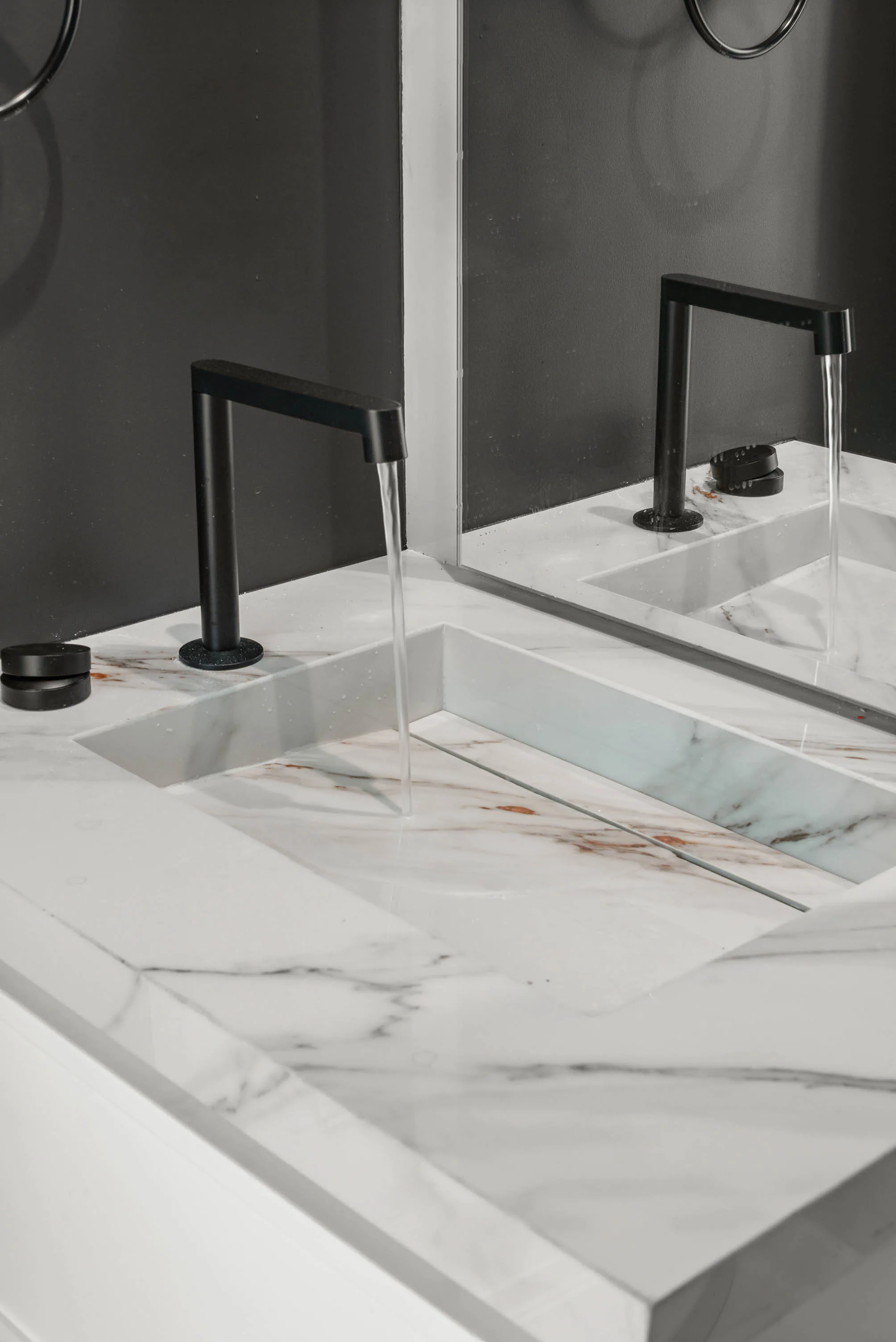 Marble vanity with black fixtures against a dark wall.