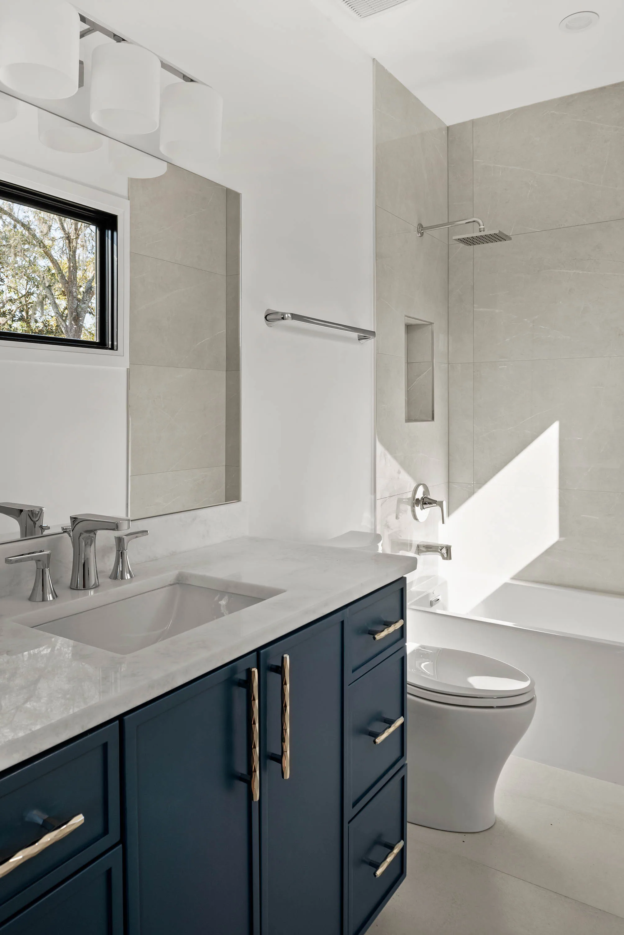 Blue vanity and white stone surfaces in a smaller bathroom.