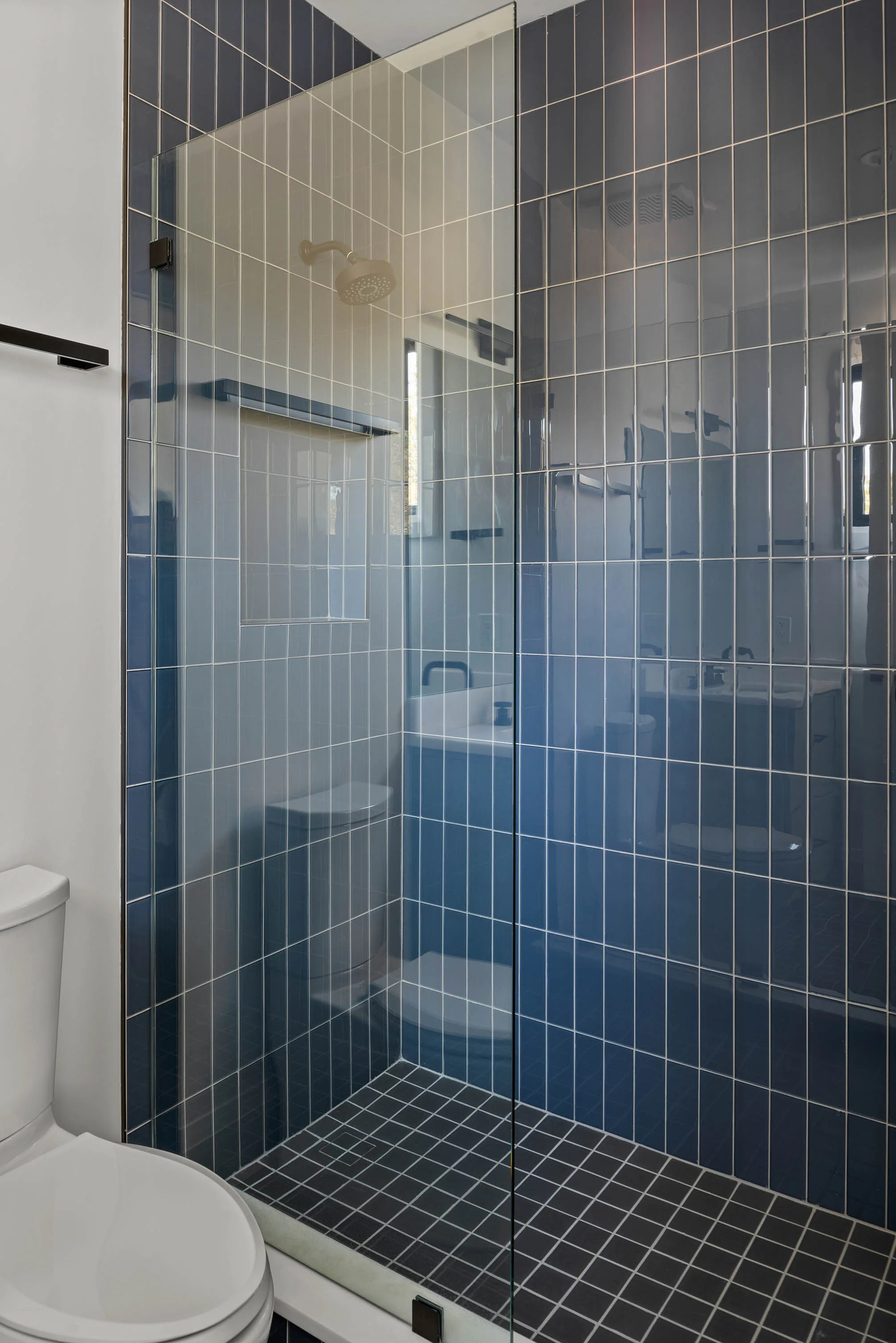 Blue tiled shower with patterned floor tile.