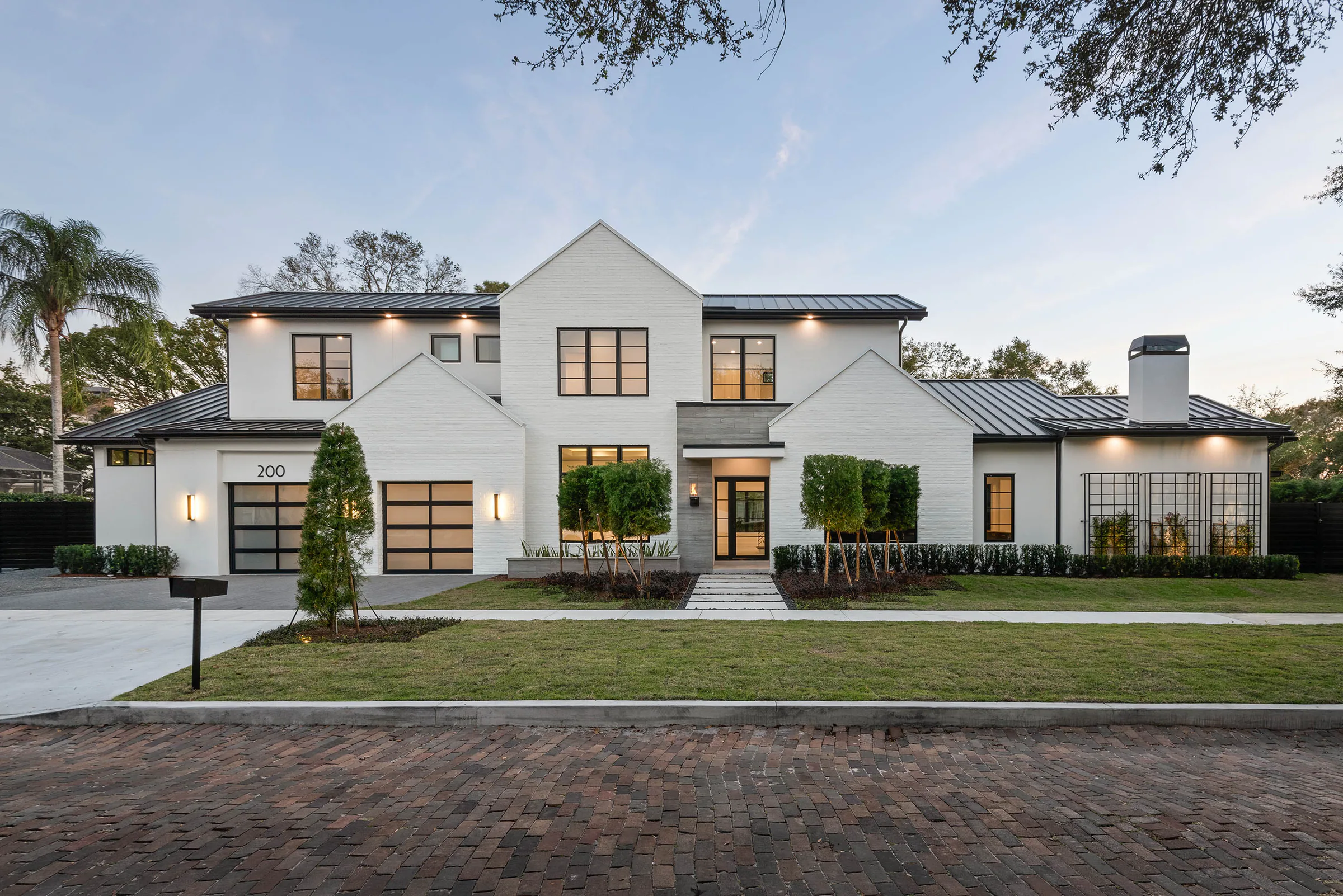 Front elevation of Oakwood with white painted brick, steep gables, black metal roofs and dark-framed windows.