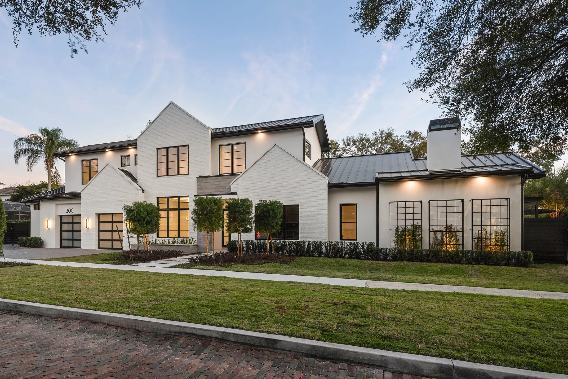 White front elevation with steep gables and black metal roofs.