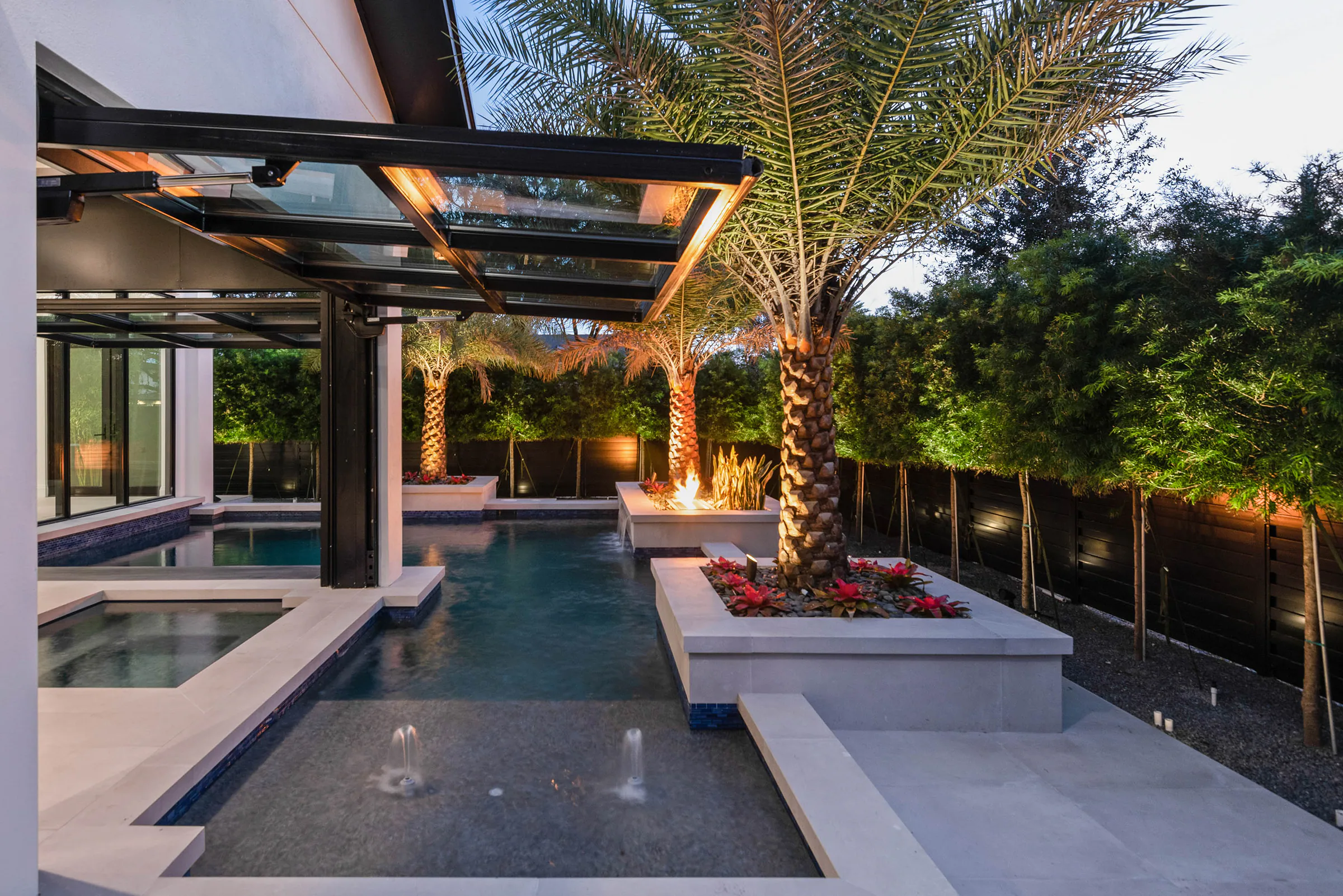 Pool pavilion and terraces illuminated at dusk. Oakwood, a custom home by Rare Builders in Orlando.