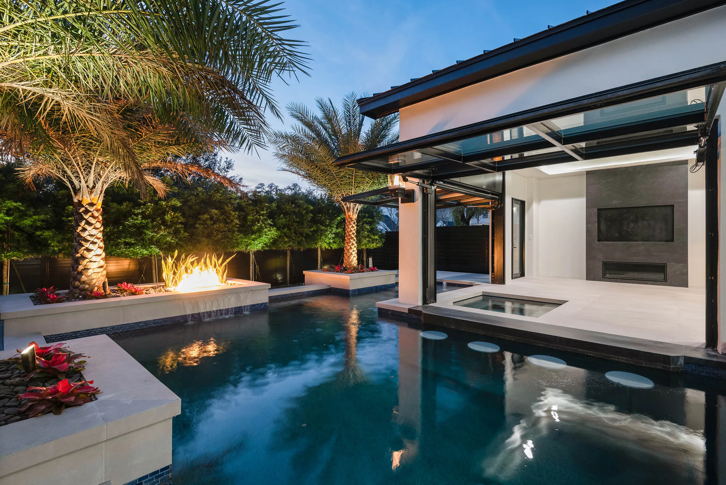 Pool and covered living spaces illuminated after sunset. Oakwood, a custom home by Rare Builders in Orlando.