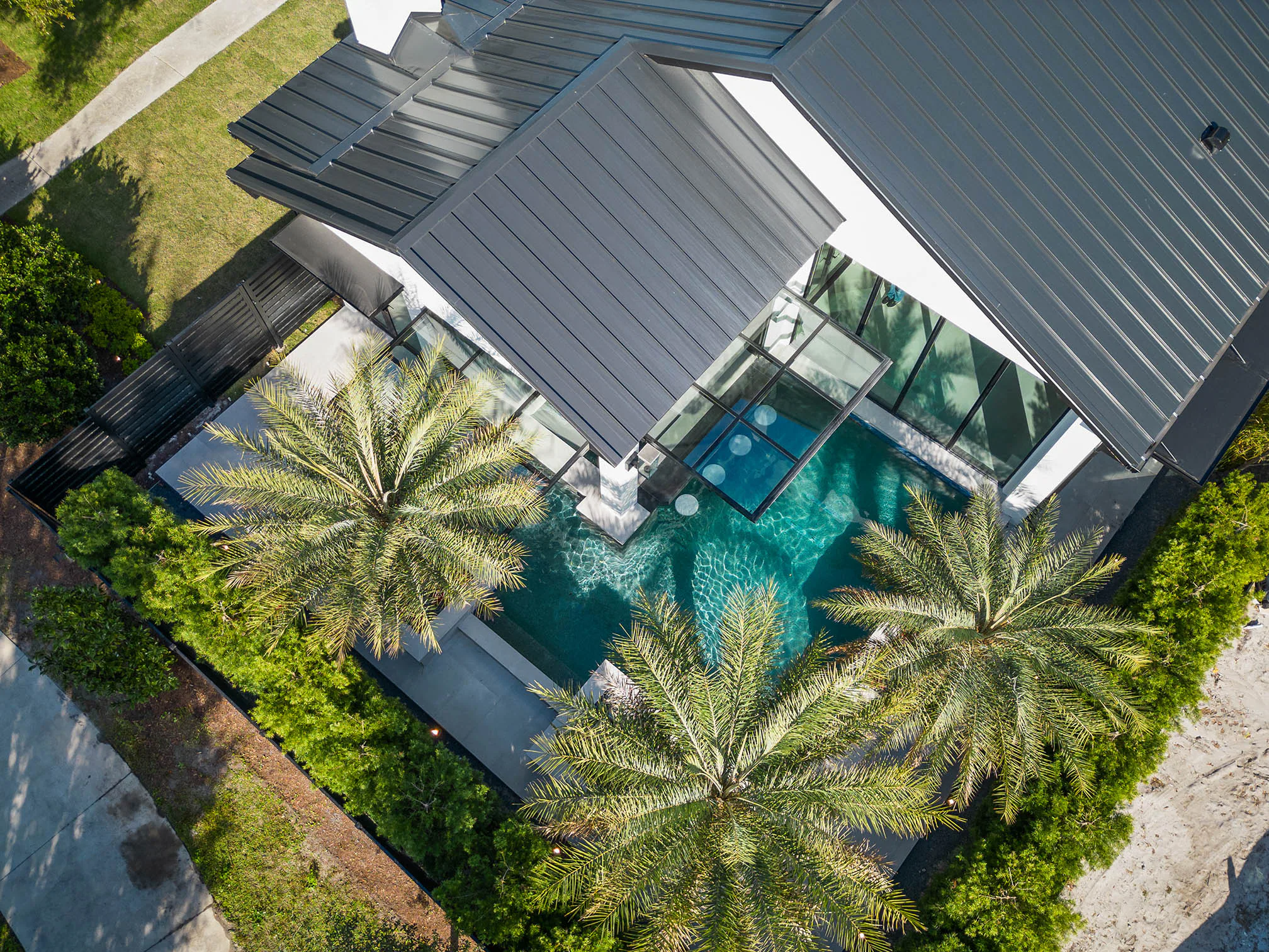 Oblique aerial view across the roofs, pool and palms.