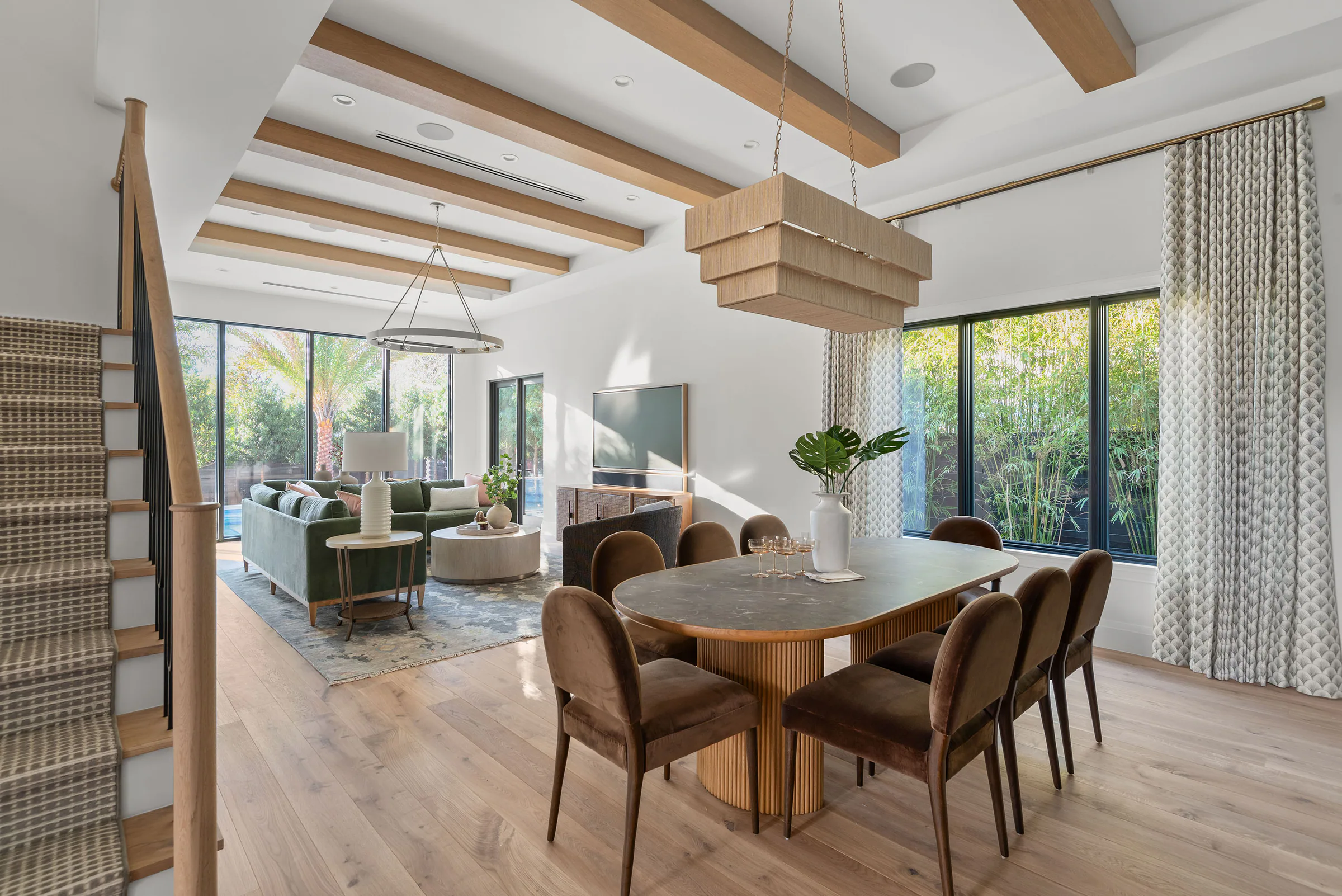Open living and dining room beneath exposed wood ceiling beams. Rockwood, a custom home by Rare Builders in Orlando.