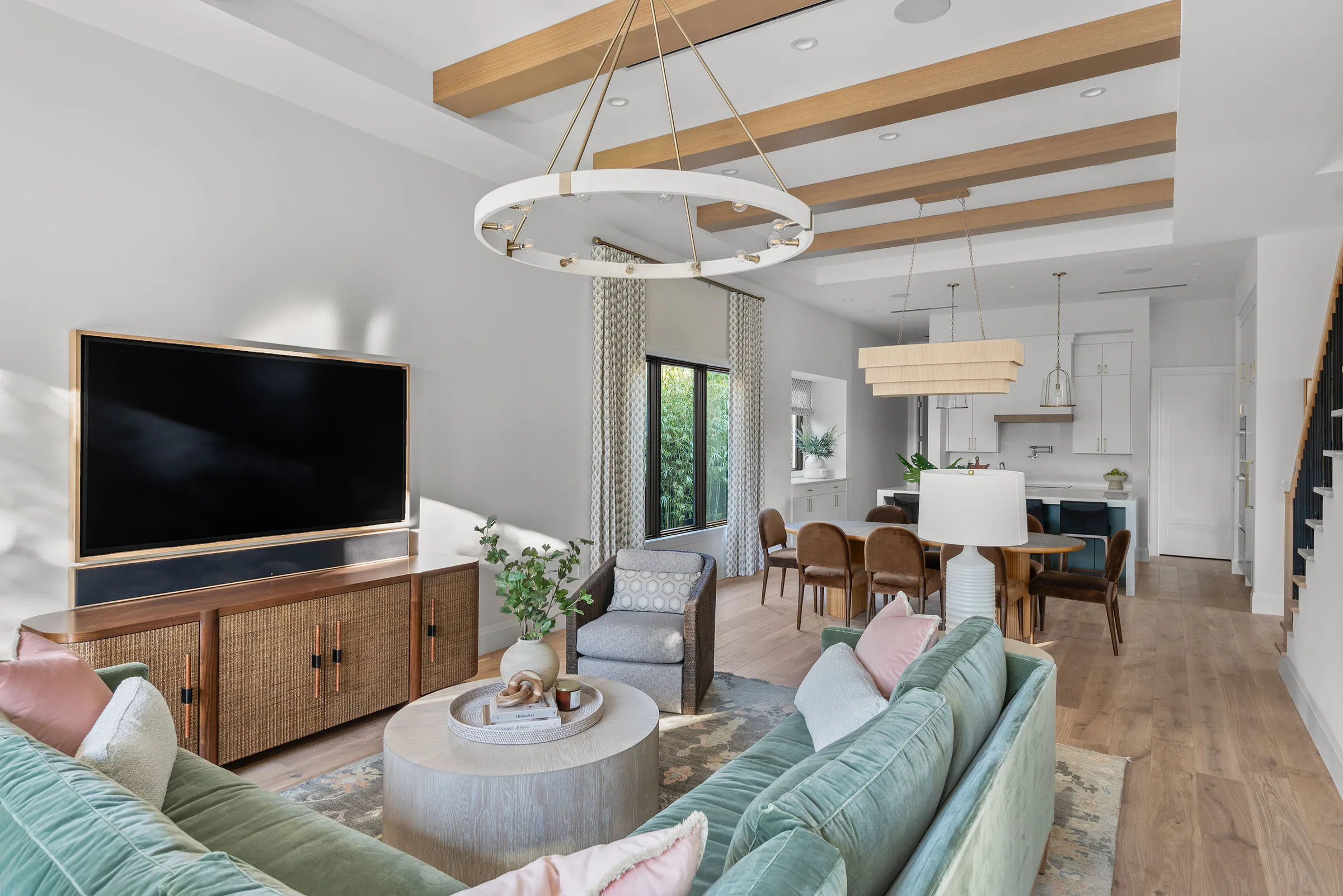 Living area with pale seating, a television wall and exposed ceiling beams. Rockwood, a custom home by Rare Builders in Orlando.