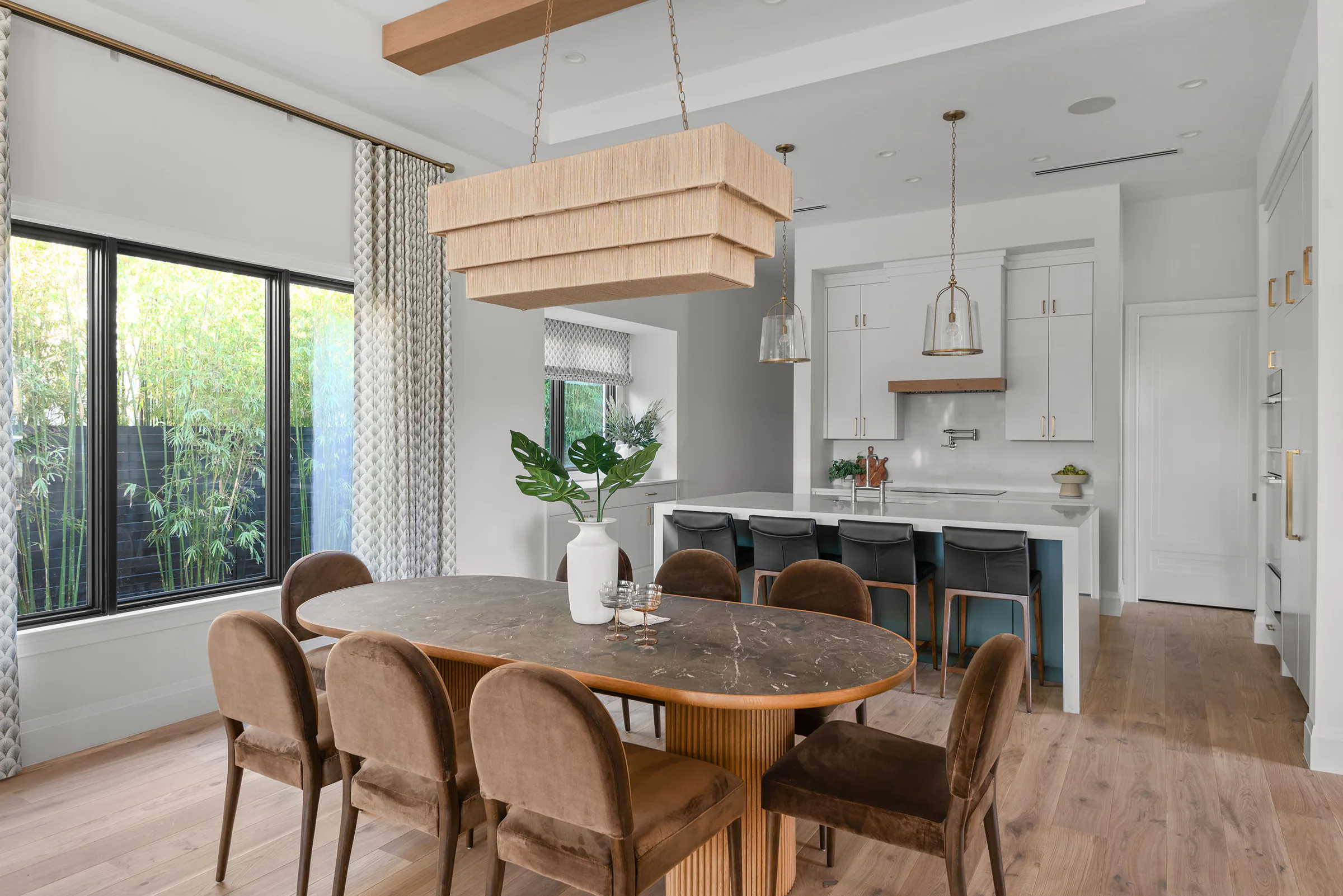 Dining table beside black-framed garden doors and the open kitchen.