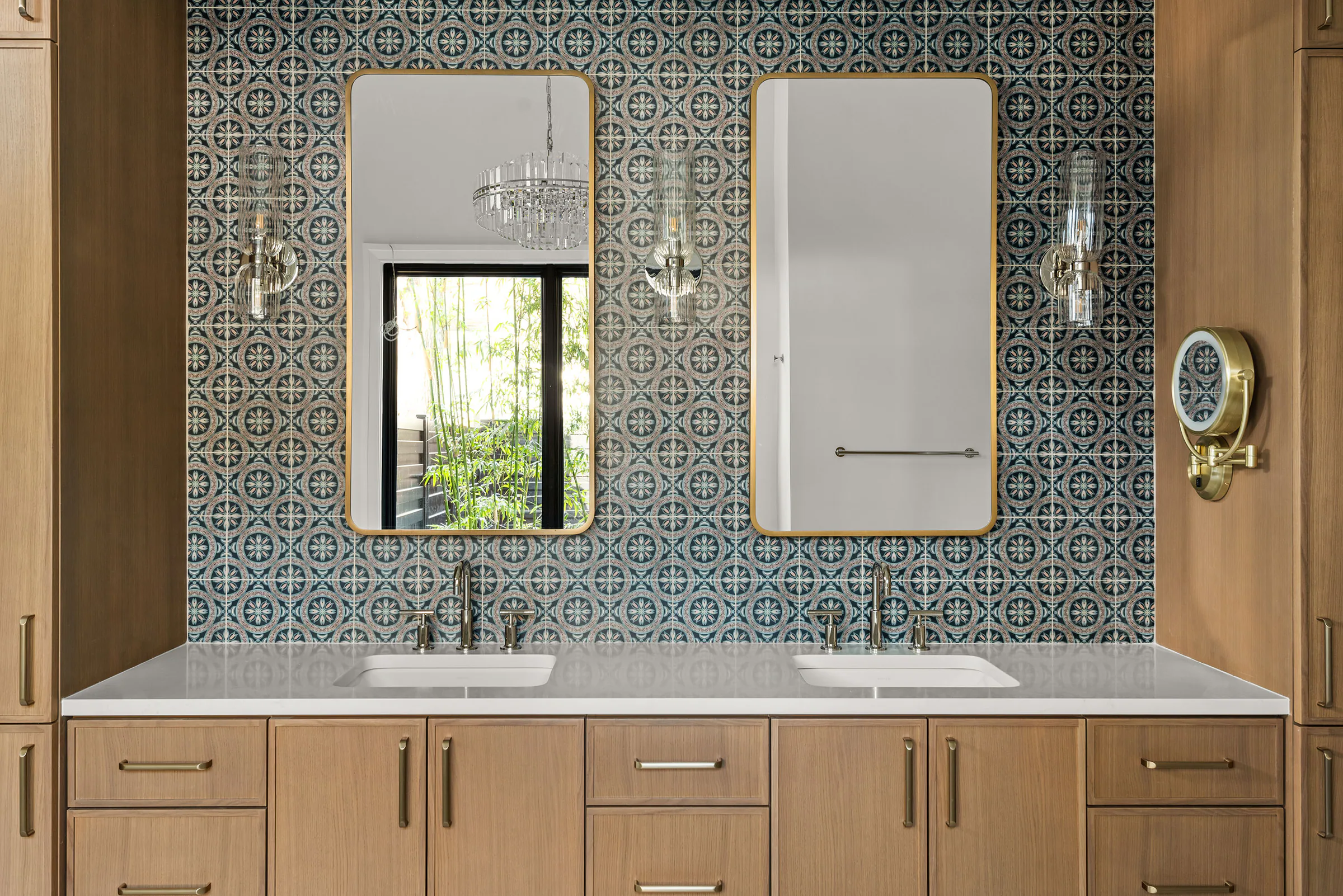 Wood vanity with twin mirrors against patterned blue tile.