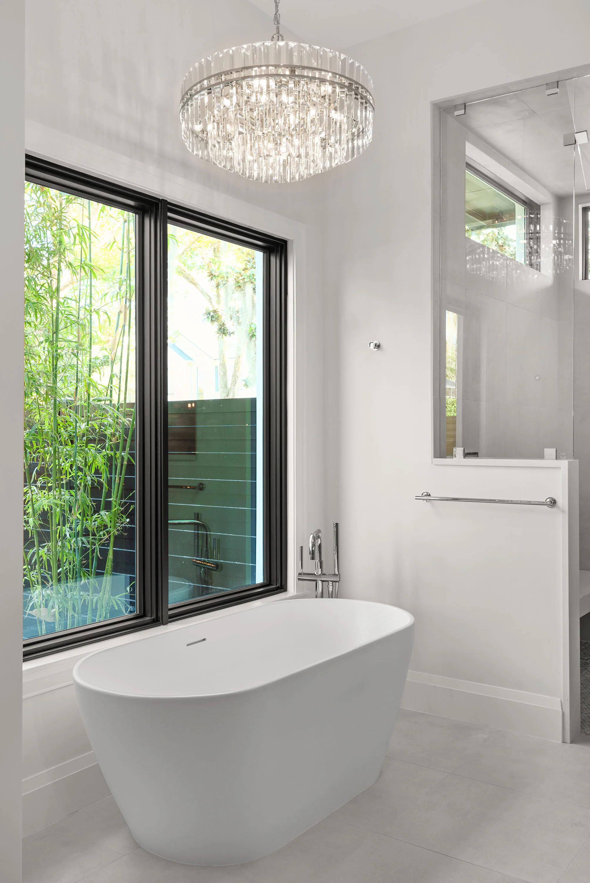 Freestanding tub beside a black-framed garden window.