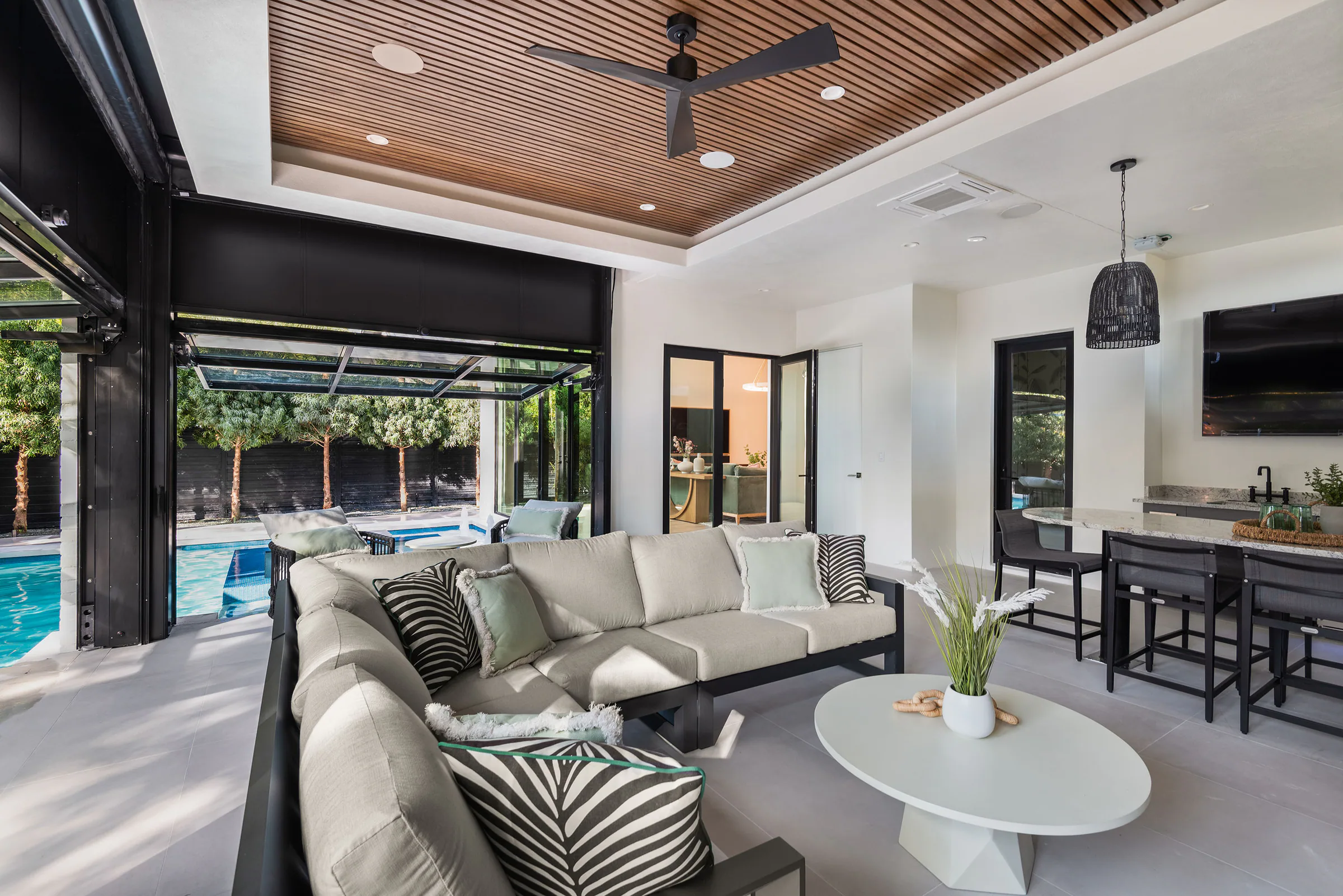 Outdoor seating and kitchen opening directly to the pool terrace. Rockwood, a custom home by Rare Builders in Orlando.