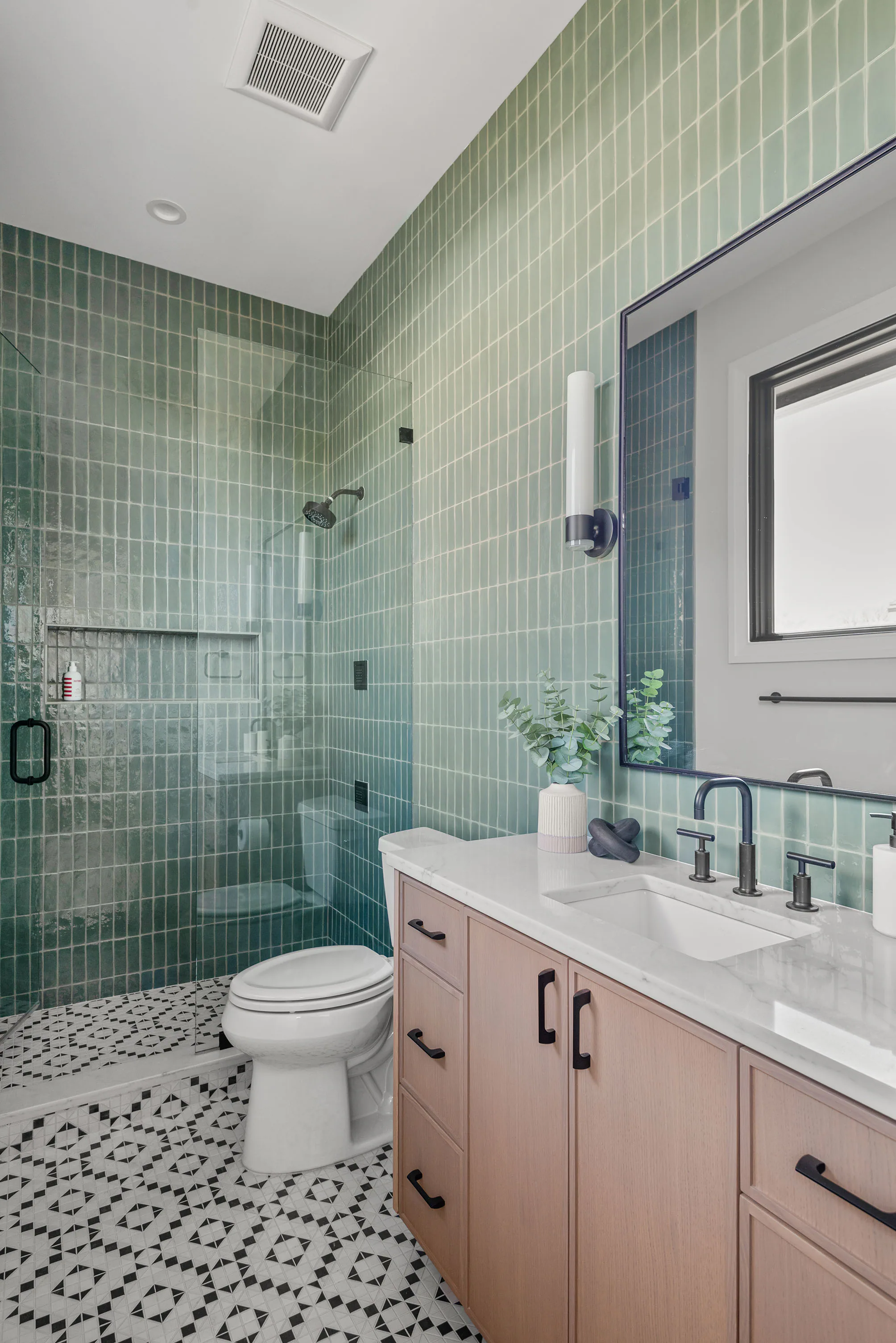 Bathroom with green wall tile, wood vanity and patterned floor. Rockwood, a custom home by Rare Builders in Orlando.