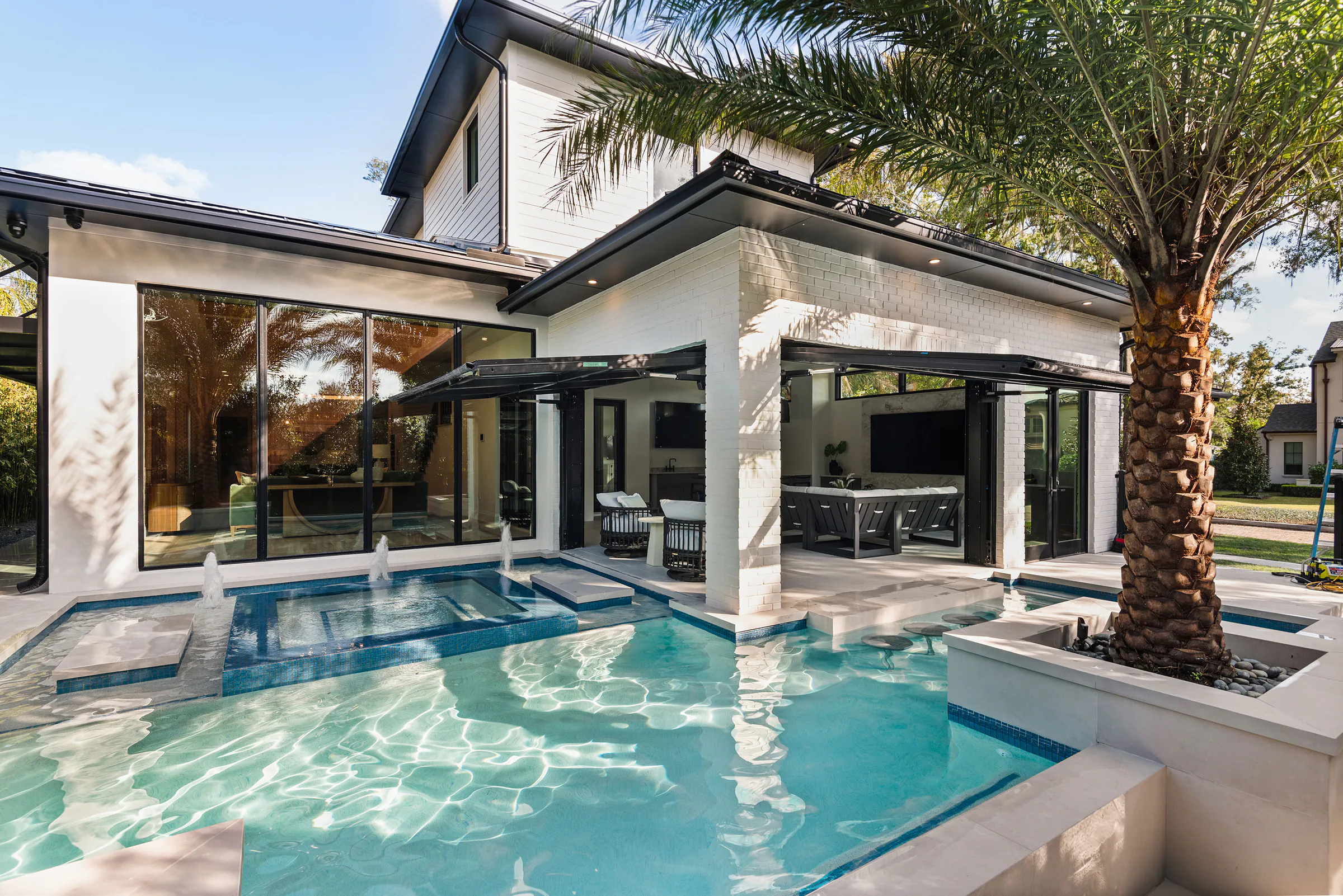 Pool and spa framed by the covered rear pavilion and palms. Rockwood, a custom home by Rare Builders in Orlando.