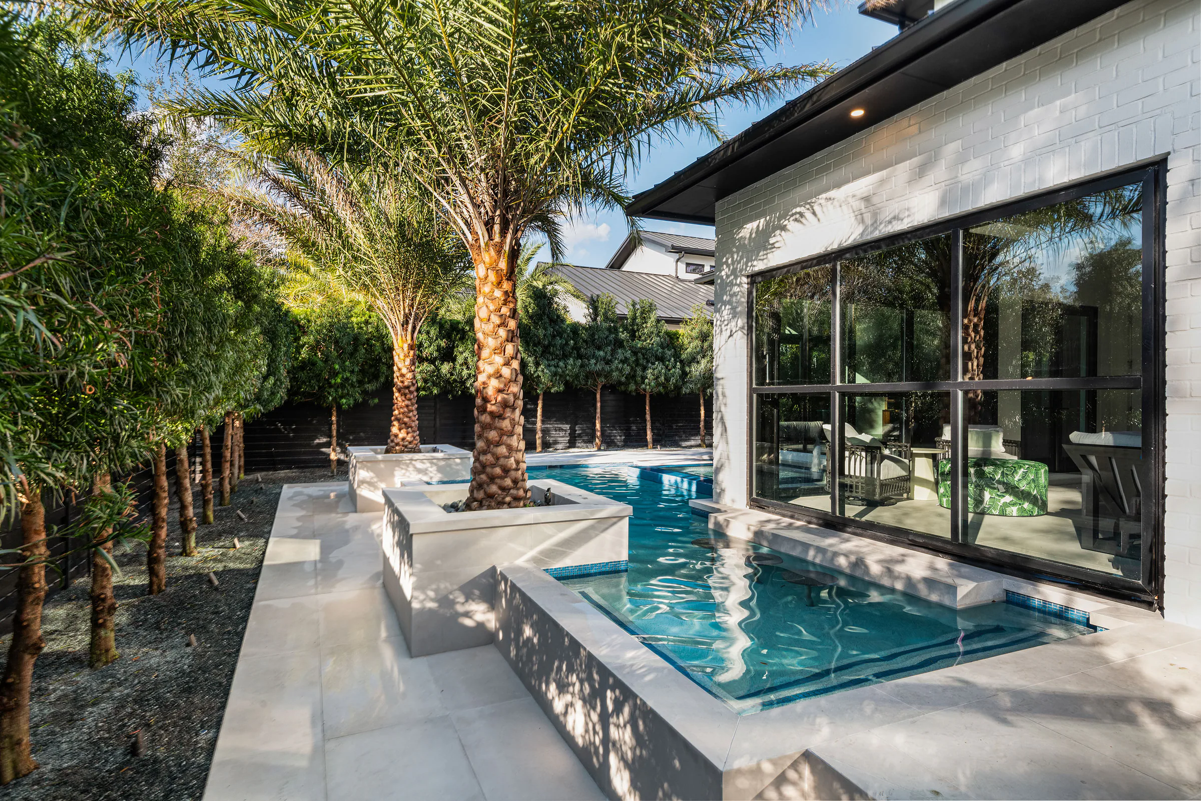 Long pool view between palms and the rear pavilion.