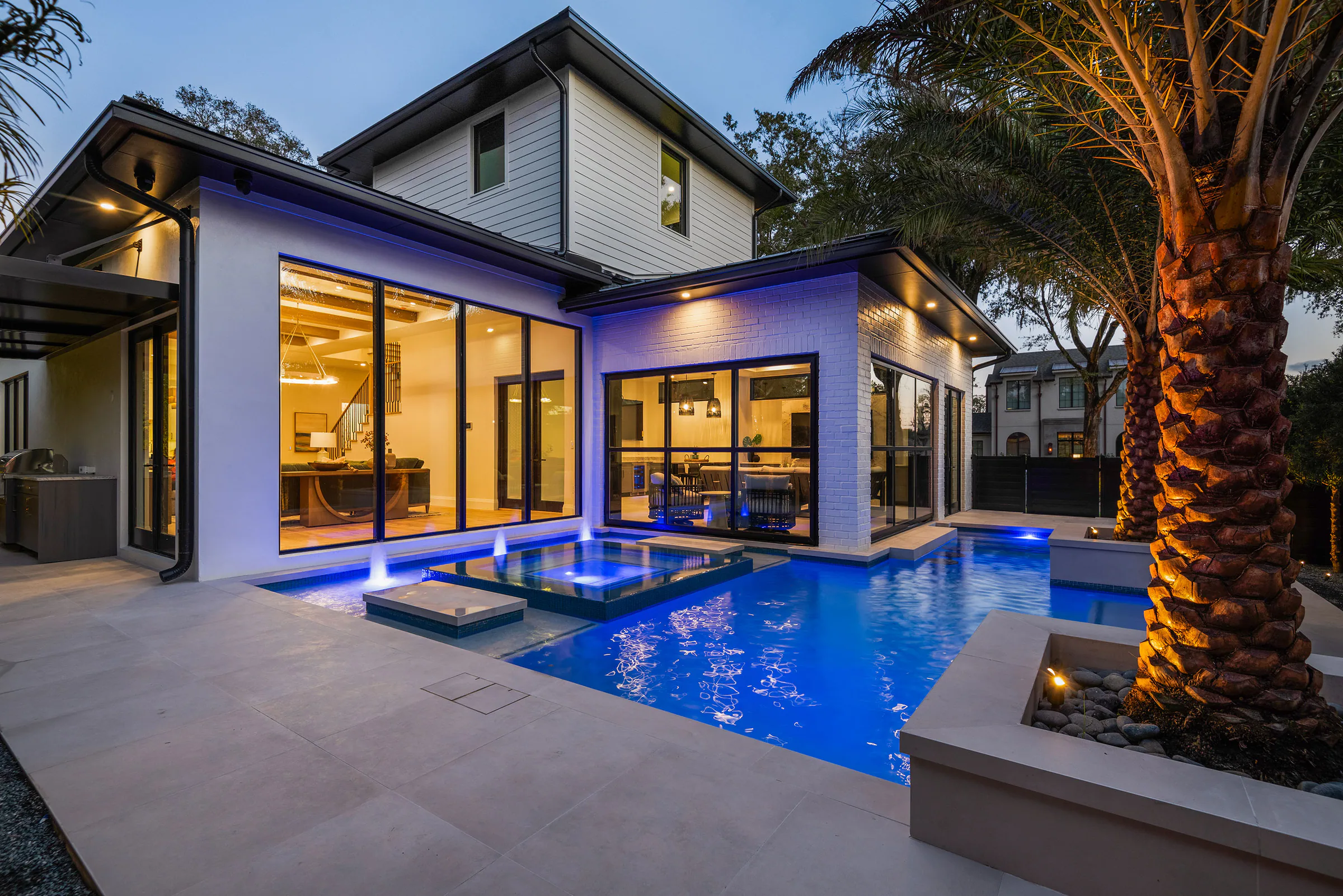 Rear pavilion and pool illuminated after sunset.