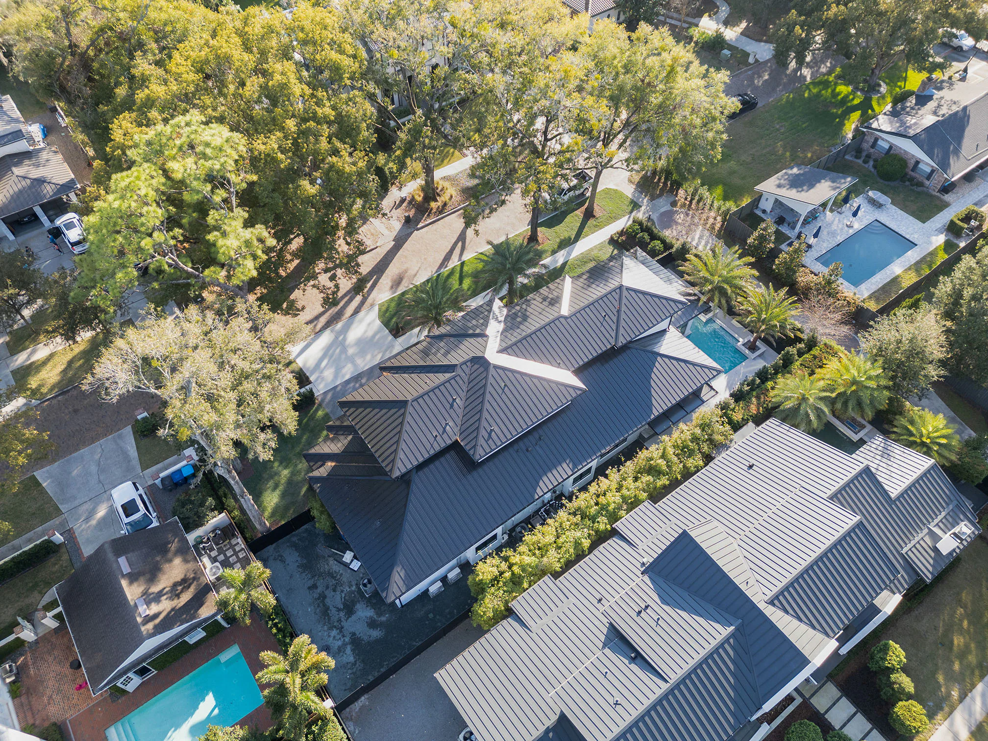 Oblique aerial view of the roofscape, pool and neighboring trees.
