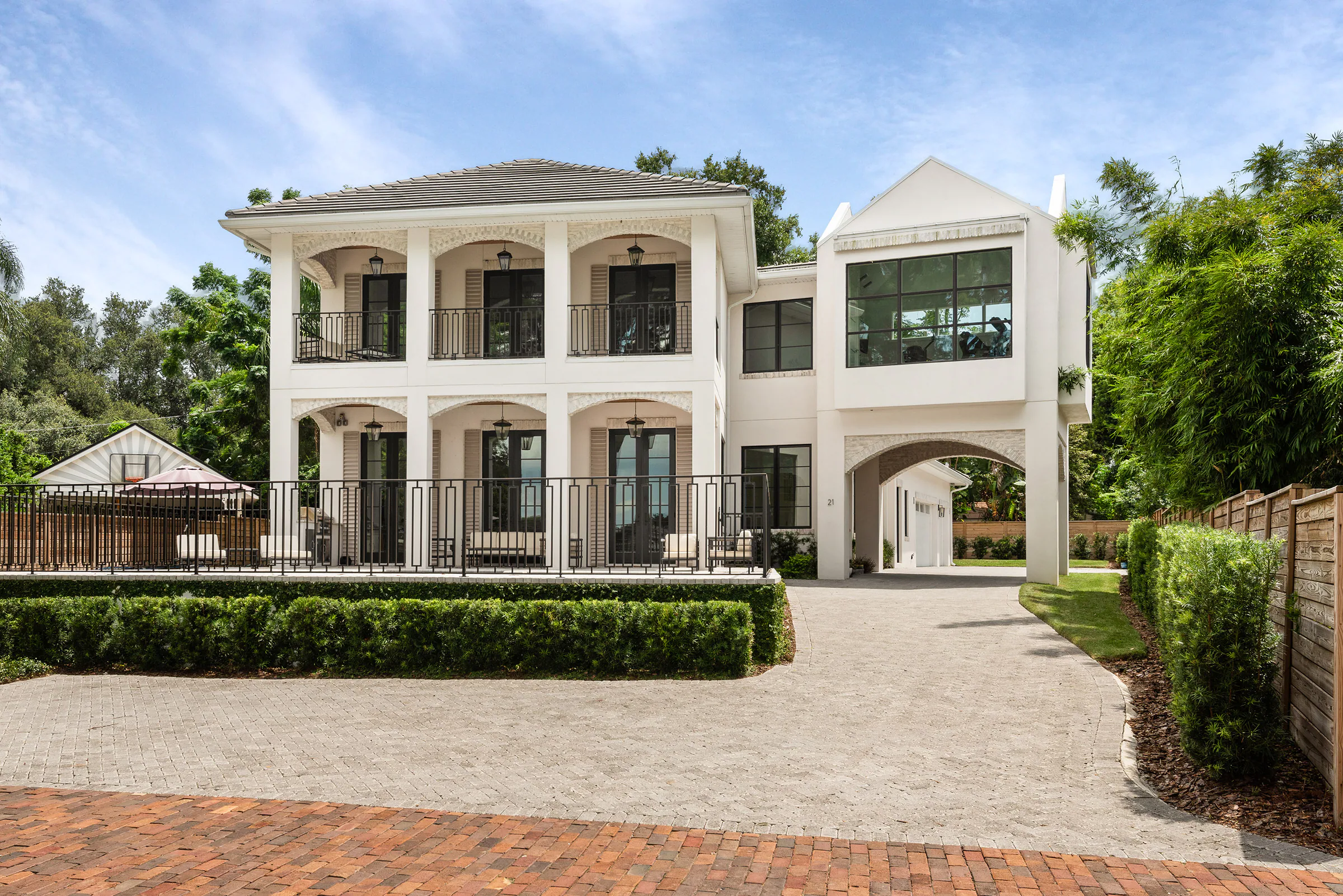 Rear elevation of Killarney with cream stucco, arched openings, balconies and a pool terrace.