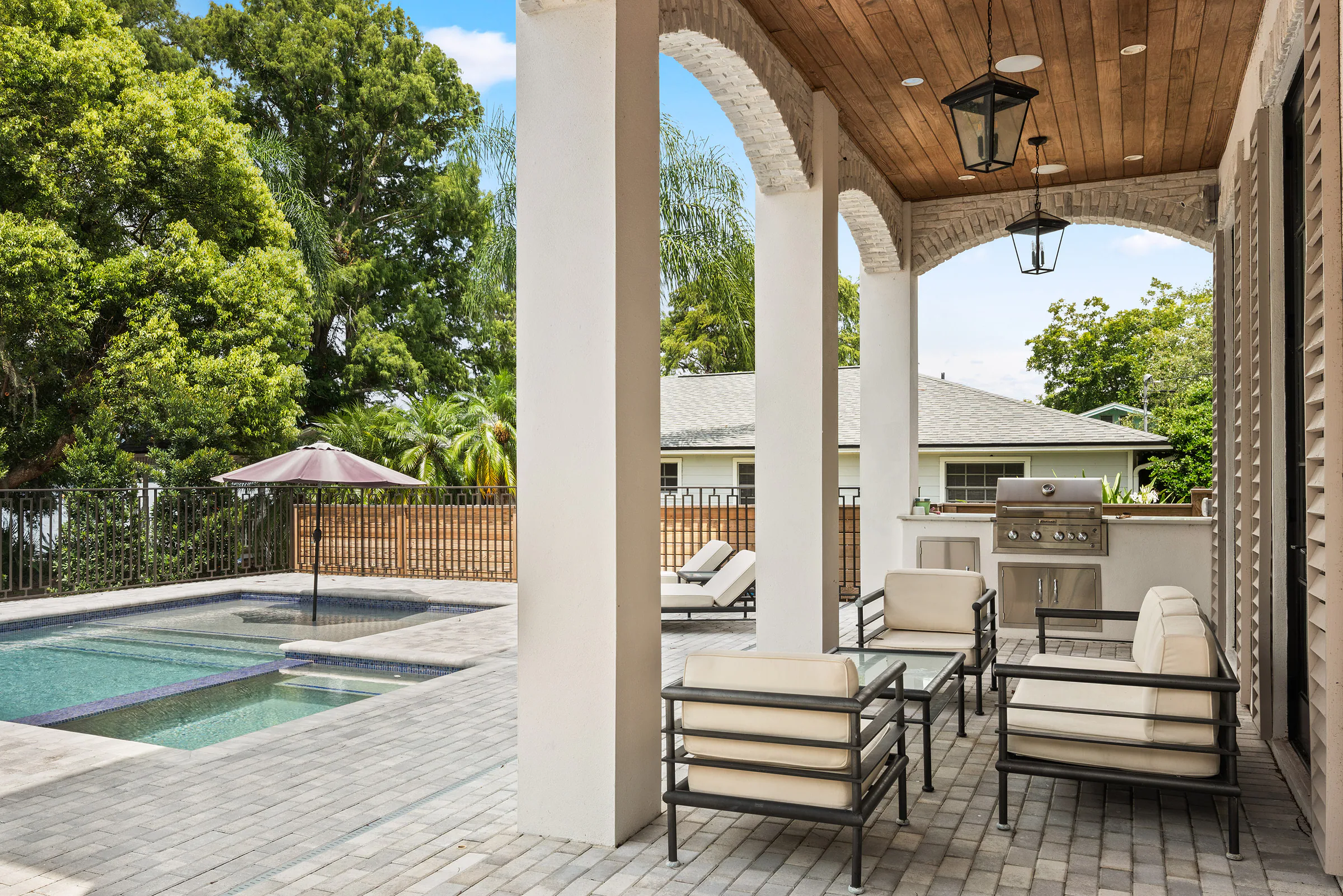 Covered Florida Room with arched openings, a wood ceiling and outdoor dining furniture.