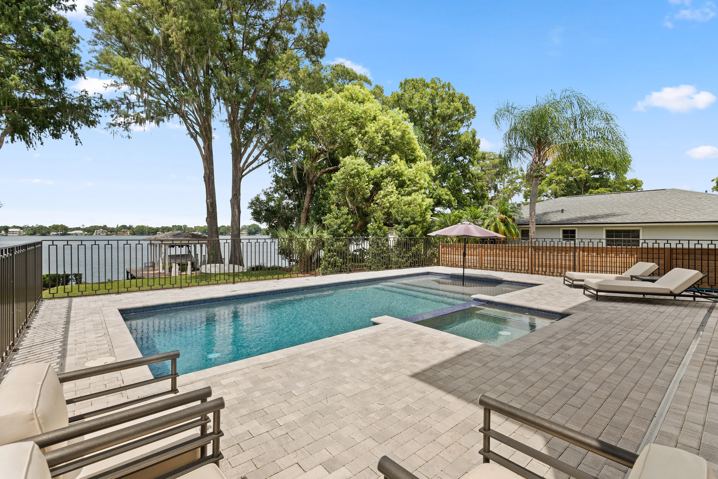 Pool terrace looking toward the lake through mature trees. Killarney, a custom home by Rare Builders in Orlando.