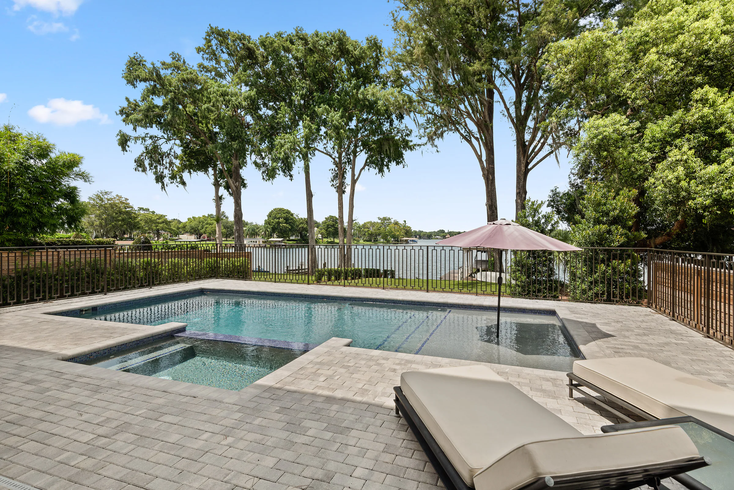 Pool, spa and pale paver terrace with lounge seating.