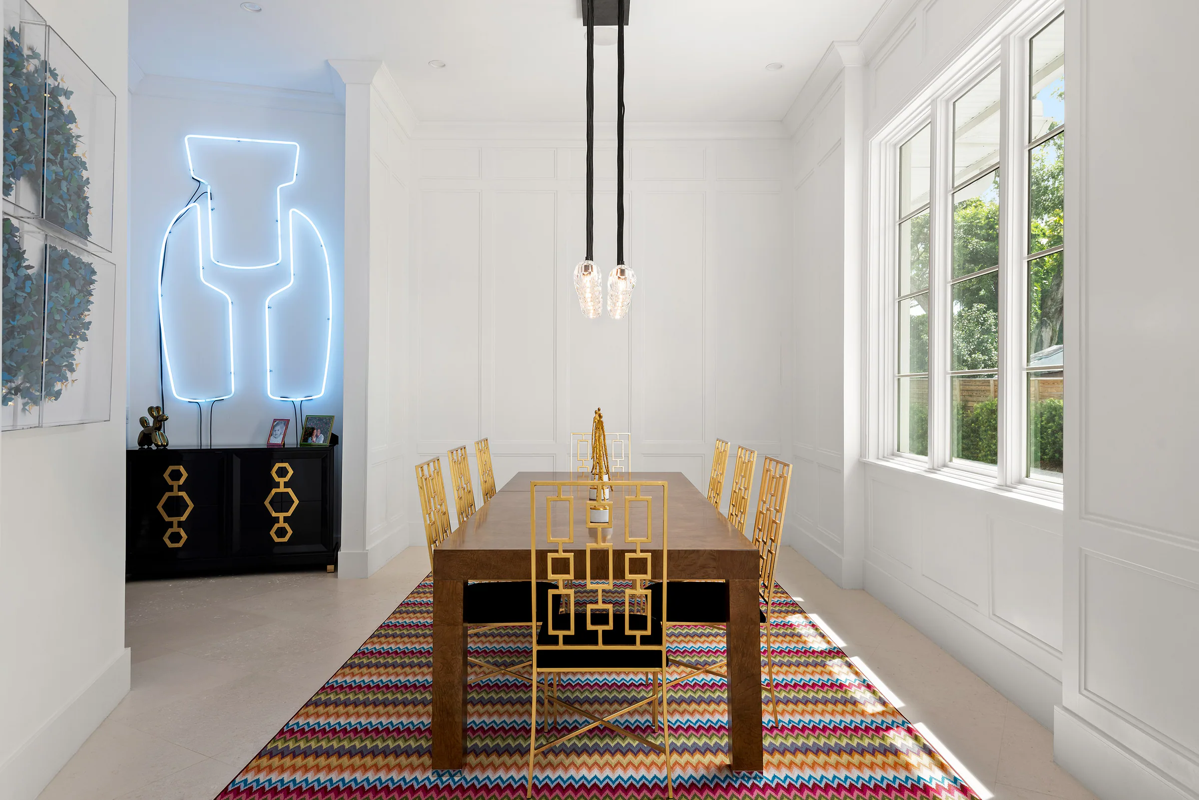 Dining room with striped rug, pendant lights and framed artwork. Killarney, a custom home by Rare Builders in Orlando.