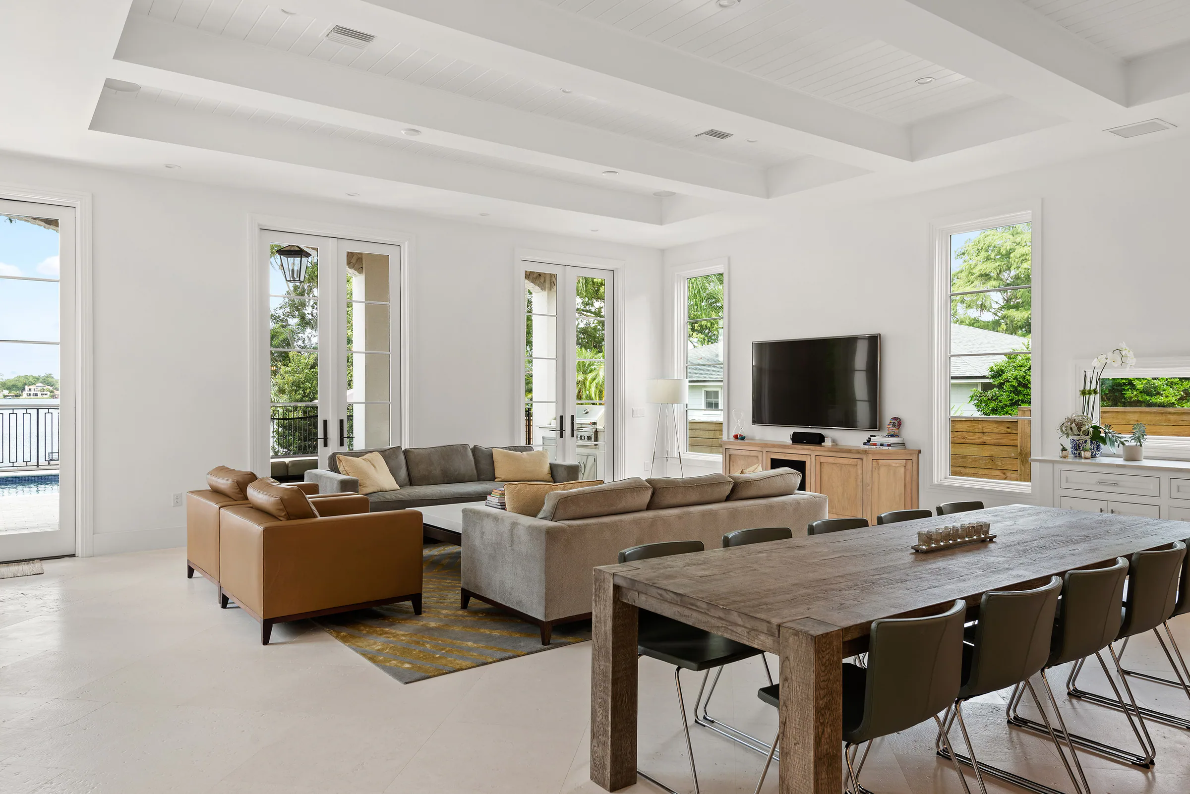 Open living room with a coffered ceiling and broad garden windows. Killarney, a custom home by Rare Builders in Orlando.