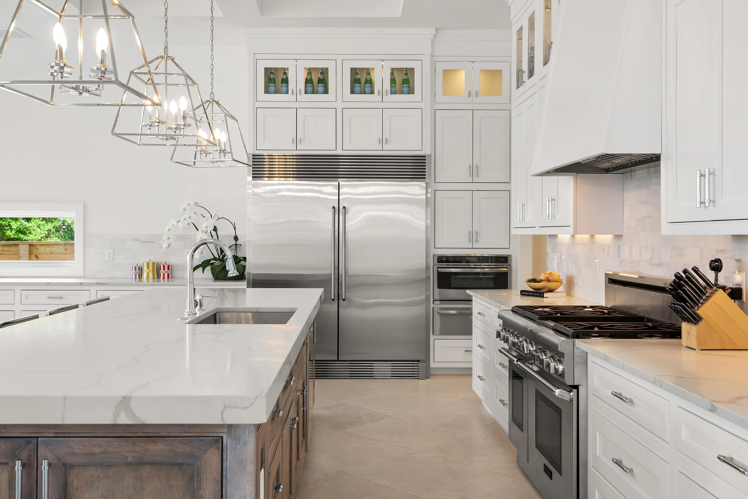 Kitchen island and stainless appliances beneath white cabinetry.