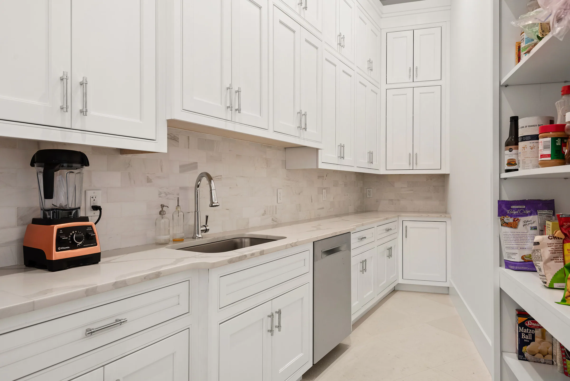 Kitchen worktop, range and white cabinetry beneath a broad window.