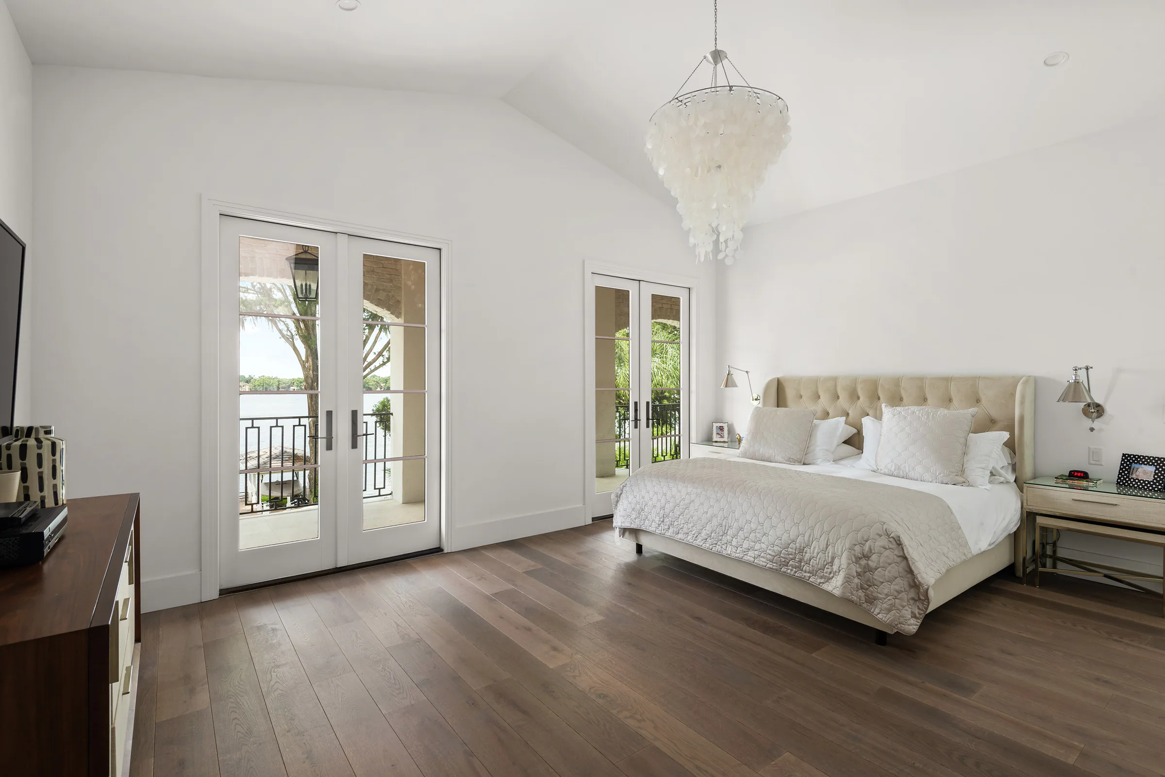 Bedroom with dark wood flooring and windows on two sides.