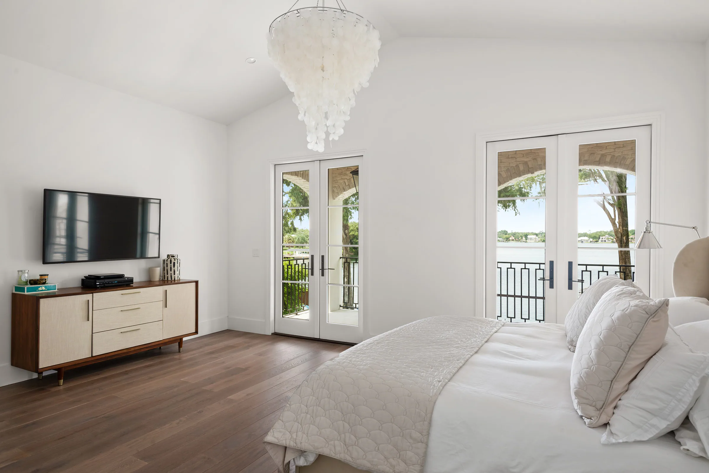 Bedroom with a pale upholstered bed and glass garden doors.