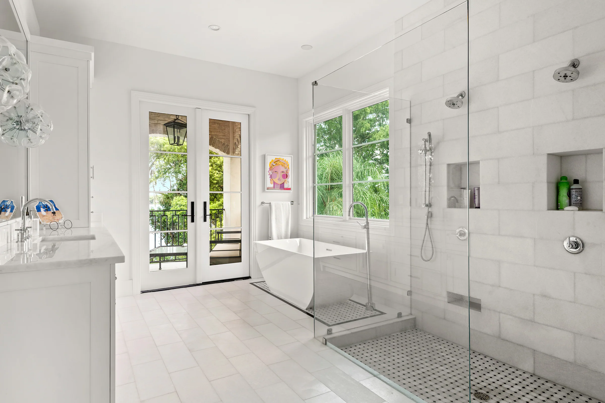 Primary bathroom with a freestanding tub, marble-tiled shower and doors to a balcony.
