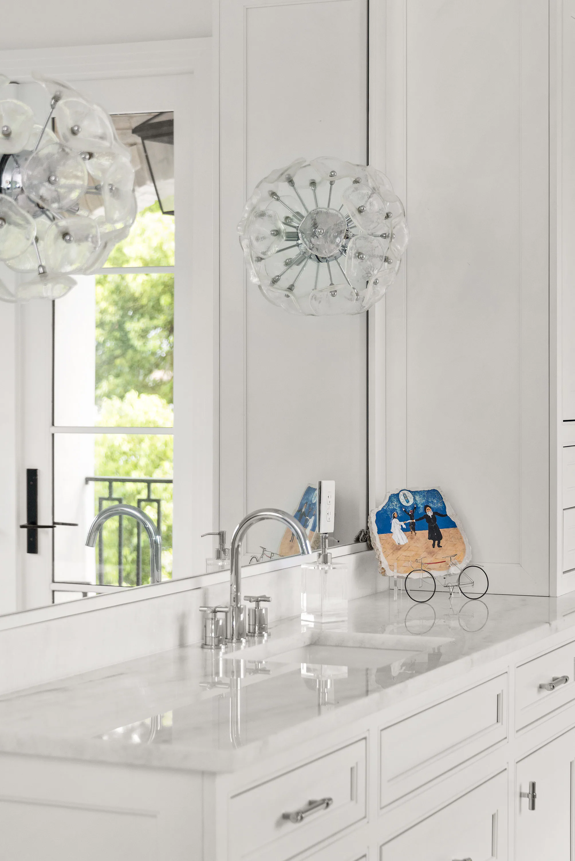 White vanity and freestanding tub beside glazed doors. Killarney, a custom home by Rare Builders in Orlando.