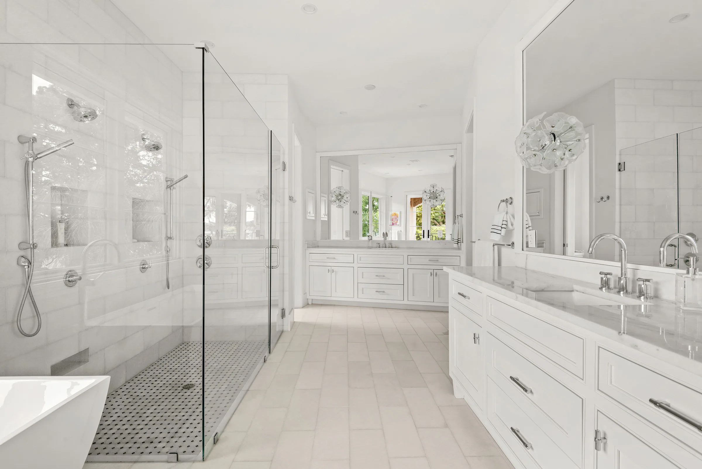 Long white vanity opposite a glass-enclosed shower. Killarney, a custom home by Rare Builders in Orlando.