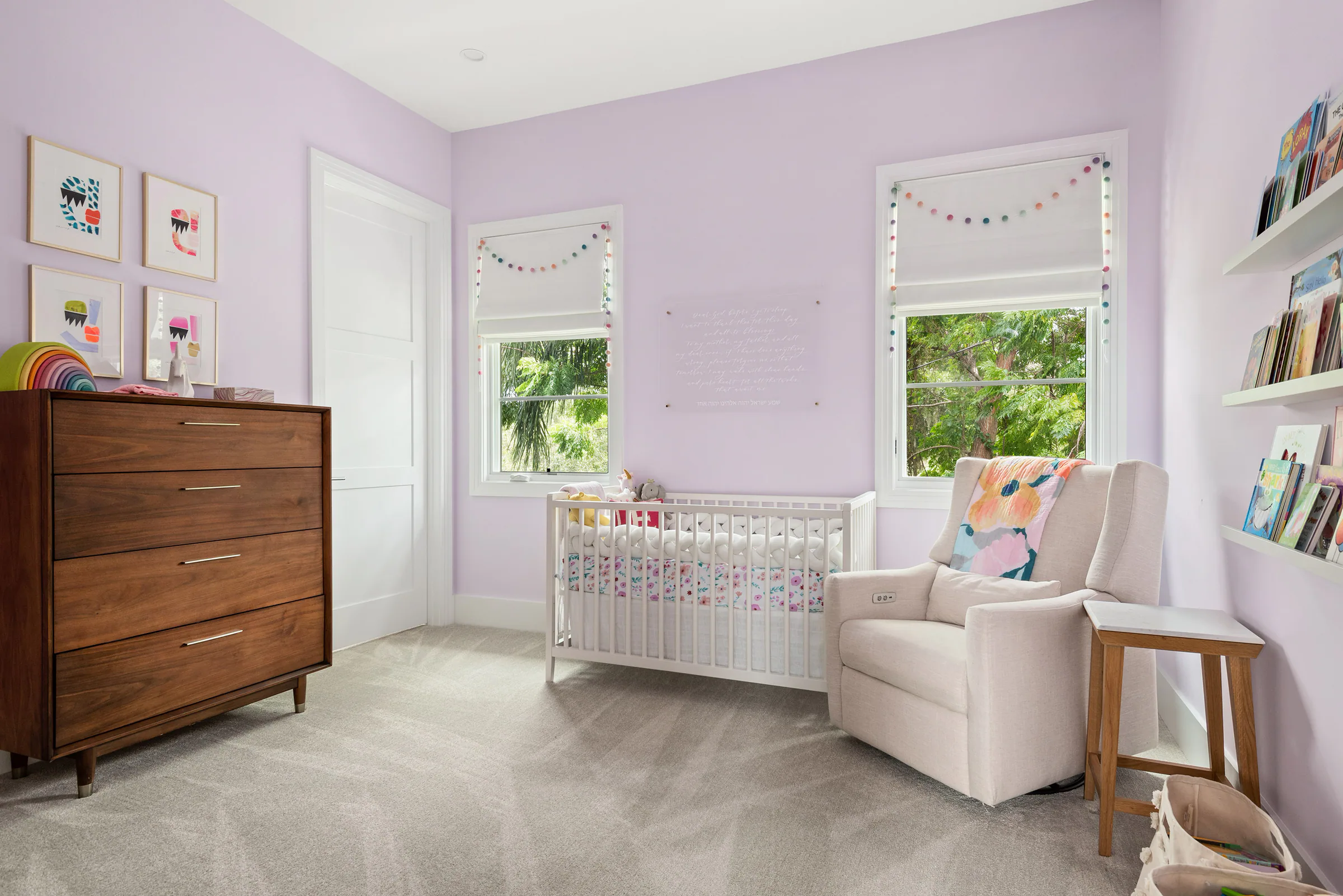 Bedroom with lavender walls, two windows and pale furnishings.