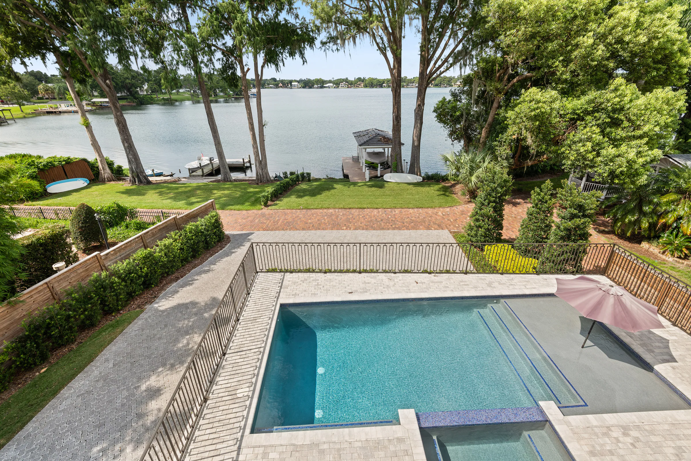 Elevated view over the pool terrace, lawn and lake beyond.