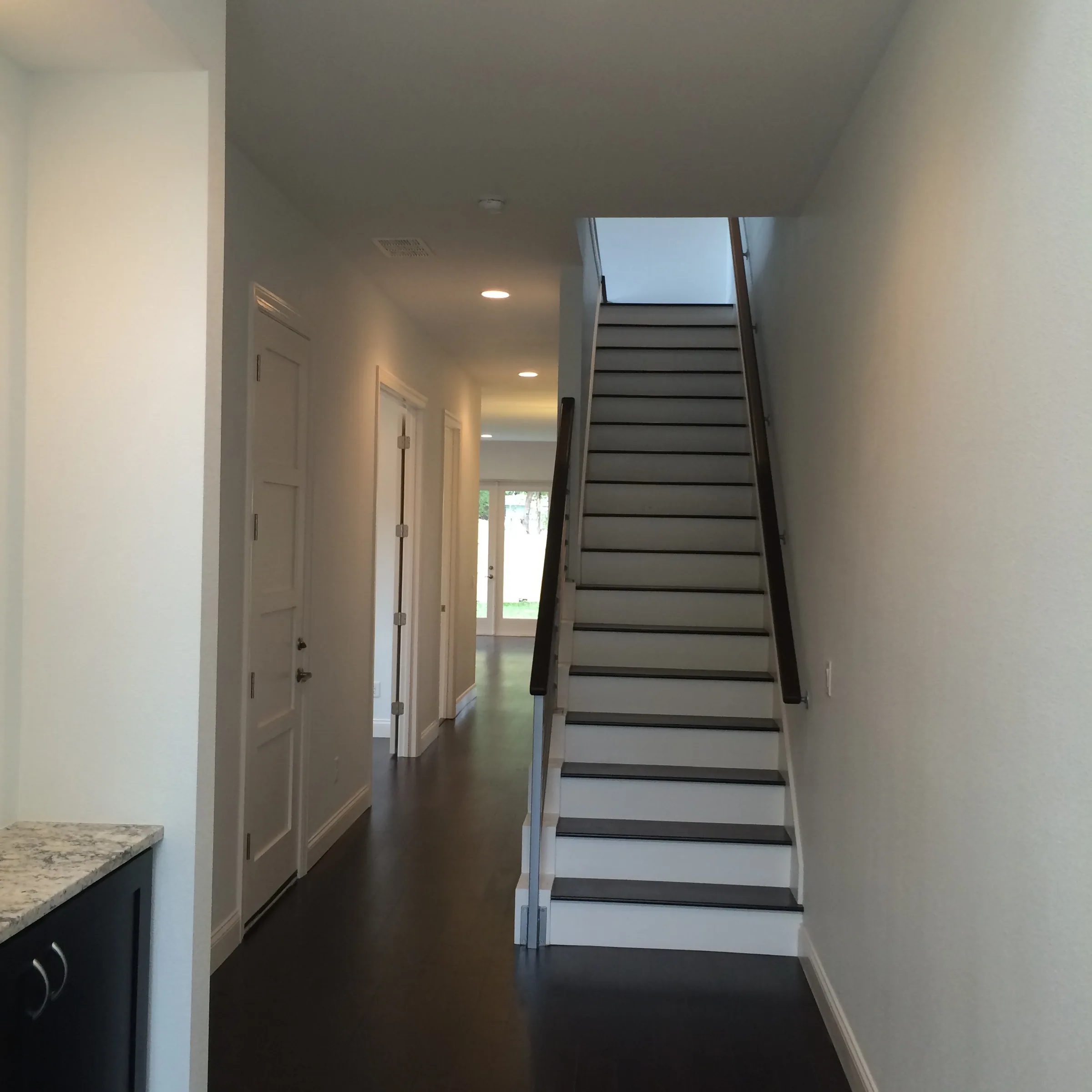 Straight Depauw staircase with dark treads and white risers beside a ground-floor hallway.