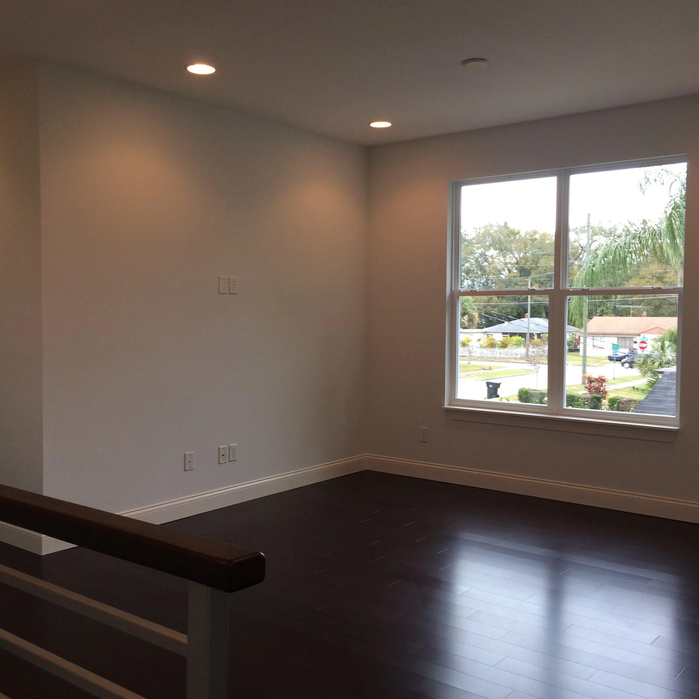 Depauw upstairs loft with dark flooring, recessed lights and a large street-facing window.