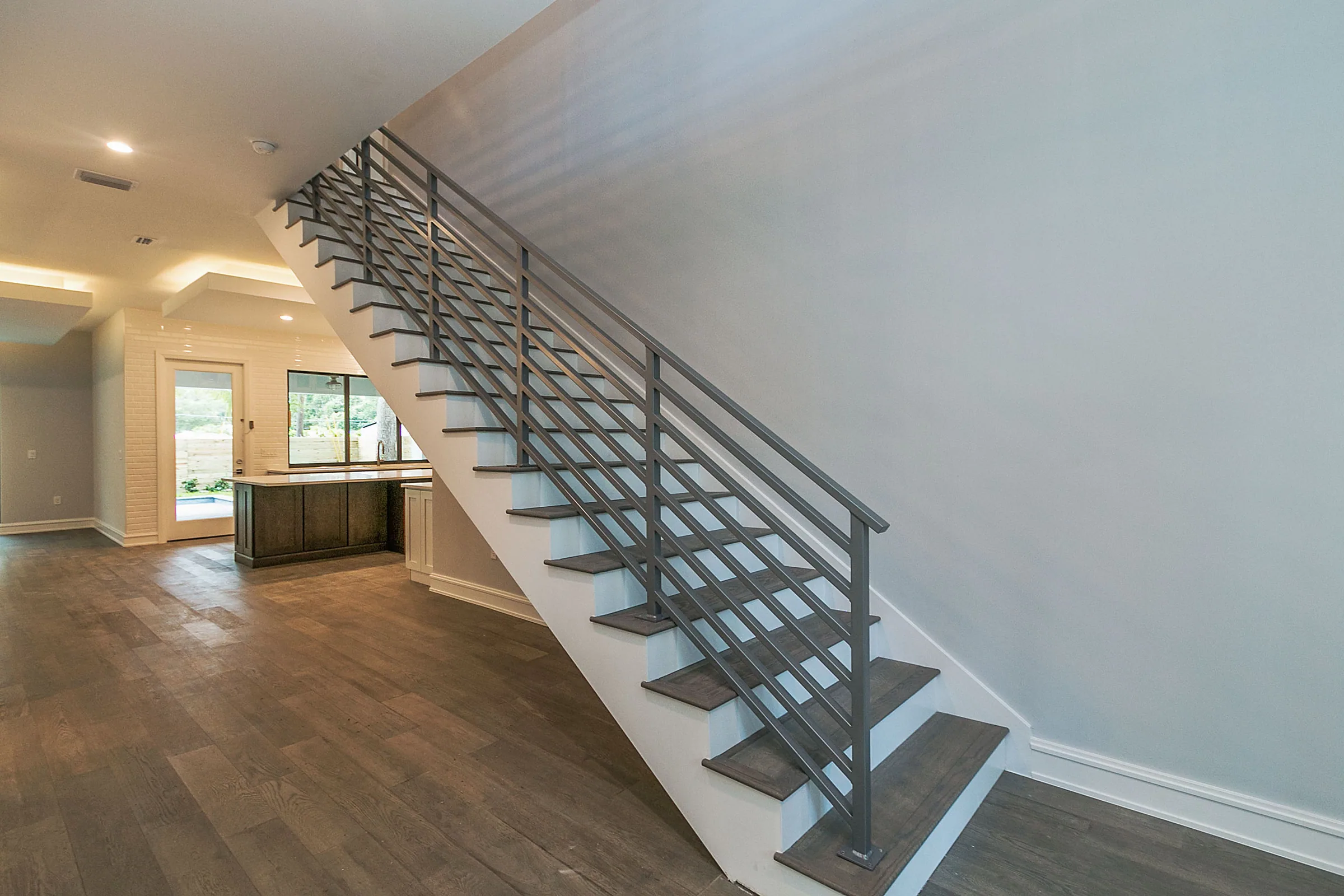 Open wood-toned staircase with dark horizontal railing rising beside the entry hall.