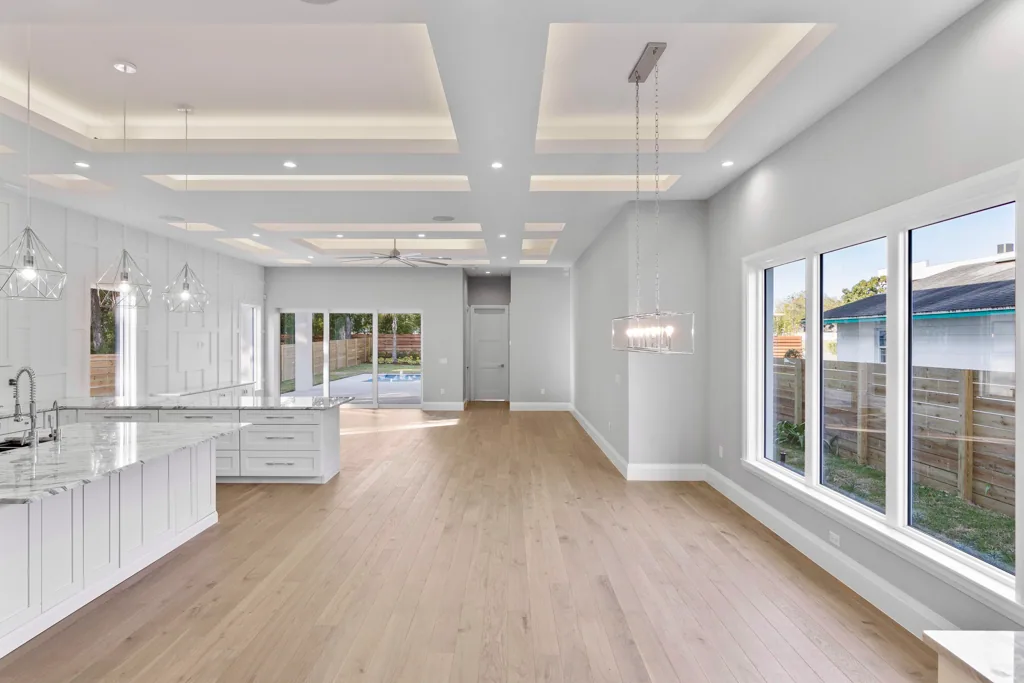 Open dining and living space at Comstock with large windows and a continuous illuminated ceiling pattern.