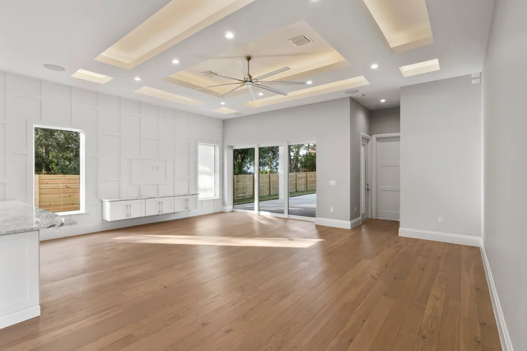 Comstock living room with white wall paneling, low cabinetry and sliding glass doors to the rear terrace.