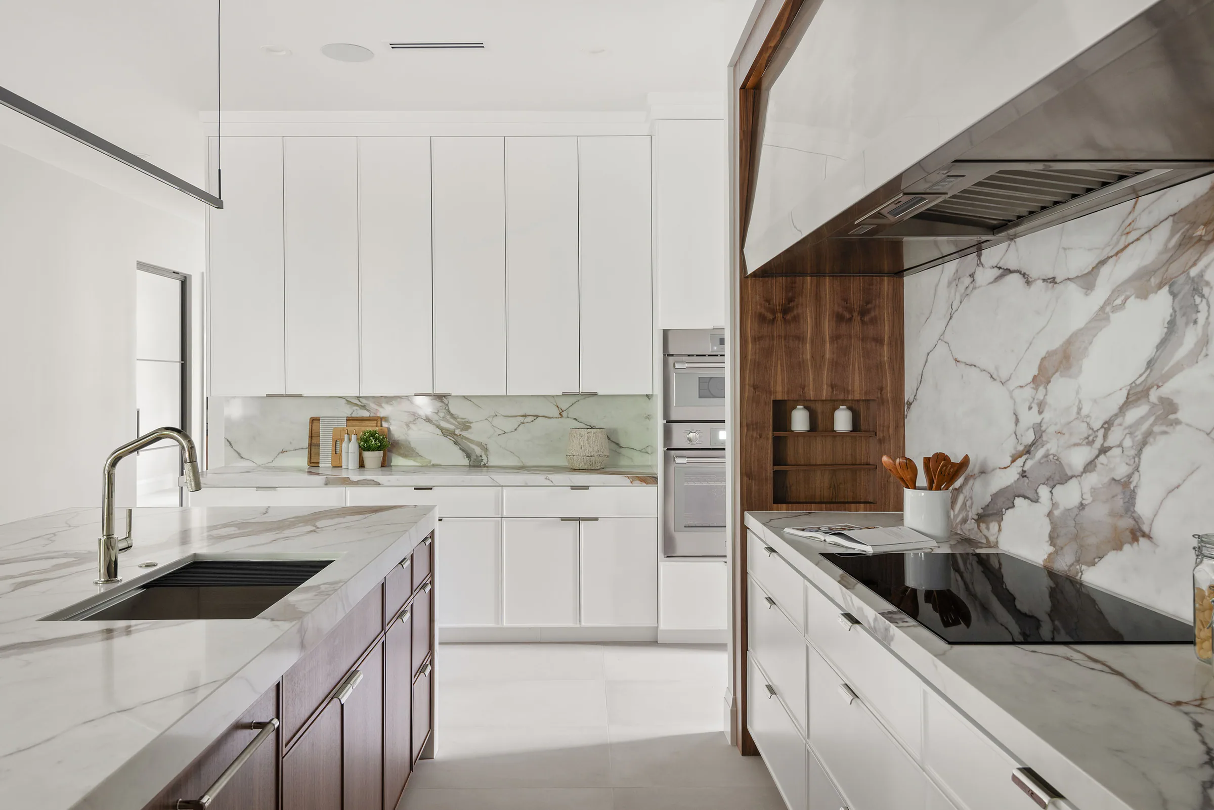 White cabinetry, marble backsplash and dark wood island. New Hampshire, a custom home by Rare Builders in Orlando.