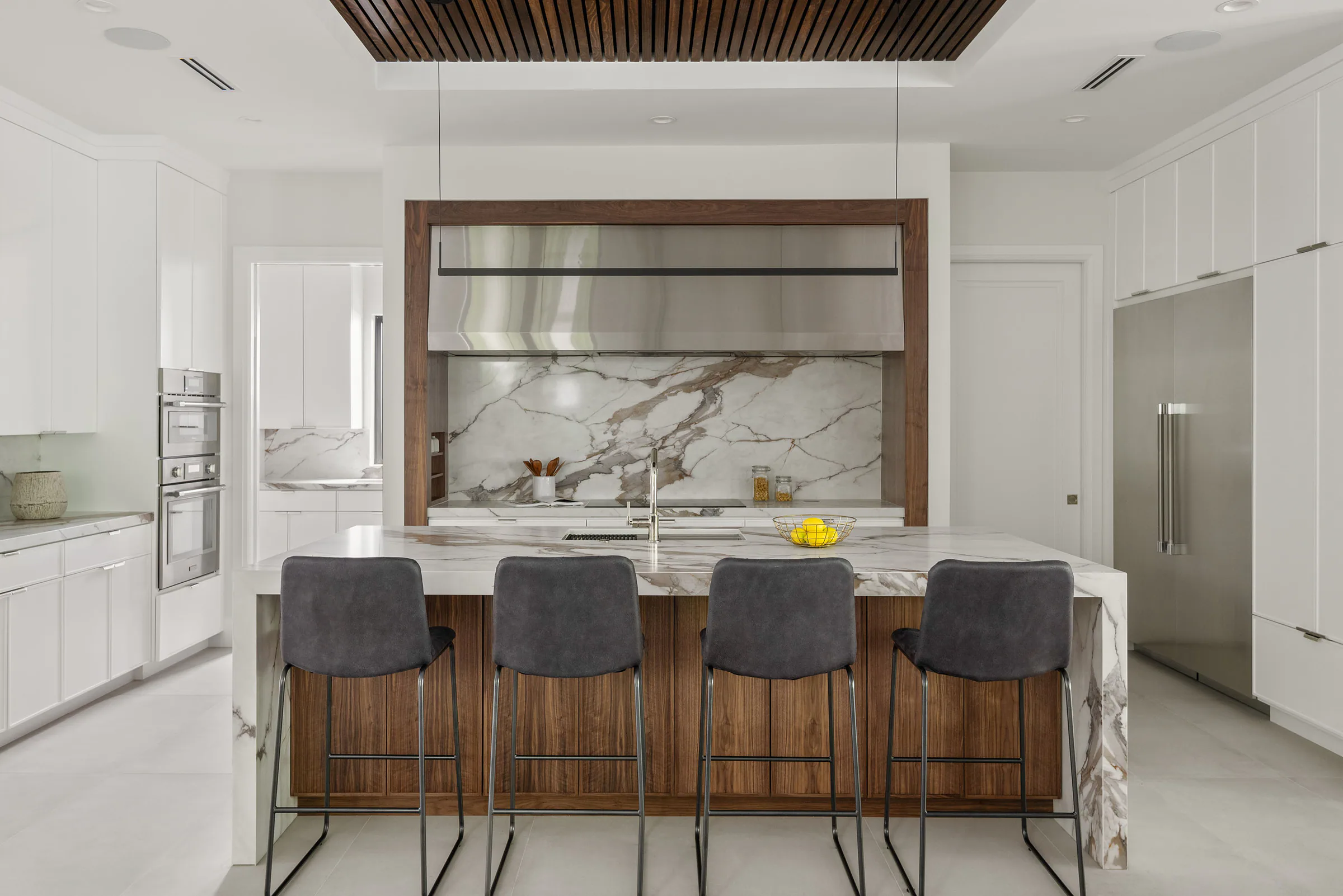 Broad kitchen island below a dark wood ceiling inset. New Hampshire, a custom home by Rare Builders in Orlando.
