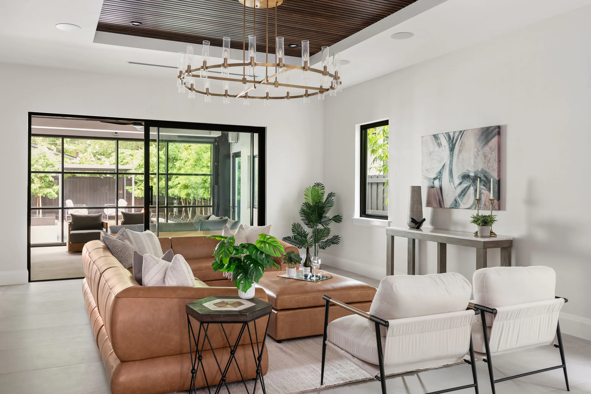 Open living and dining room with pale seating and garden doors. New Hampshire, a custom home by Rare Builders in Orlando.