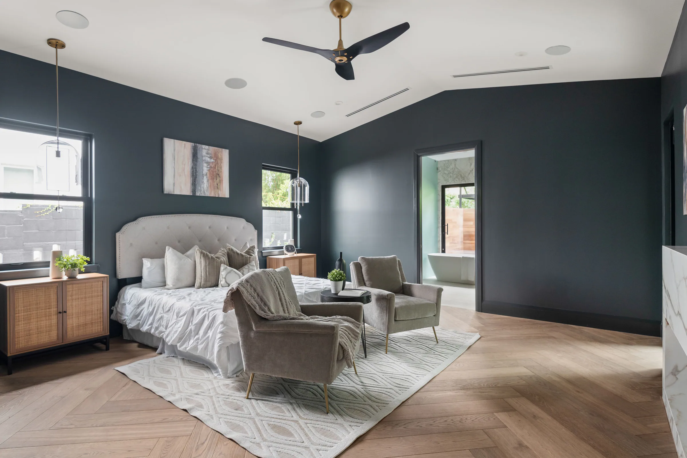 Bedroom with deep blue walls and an upholstered bed. New Hampshire, a custom home by Rare Builders in Orlando.
