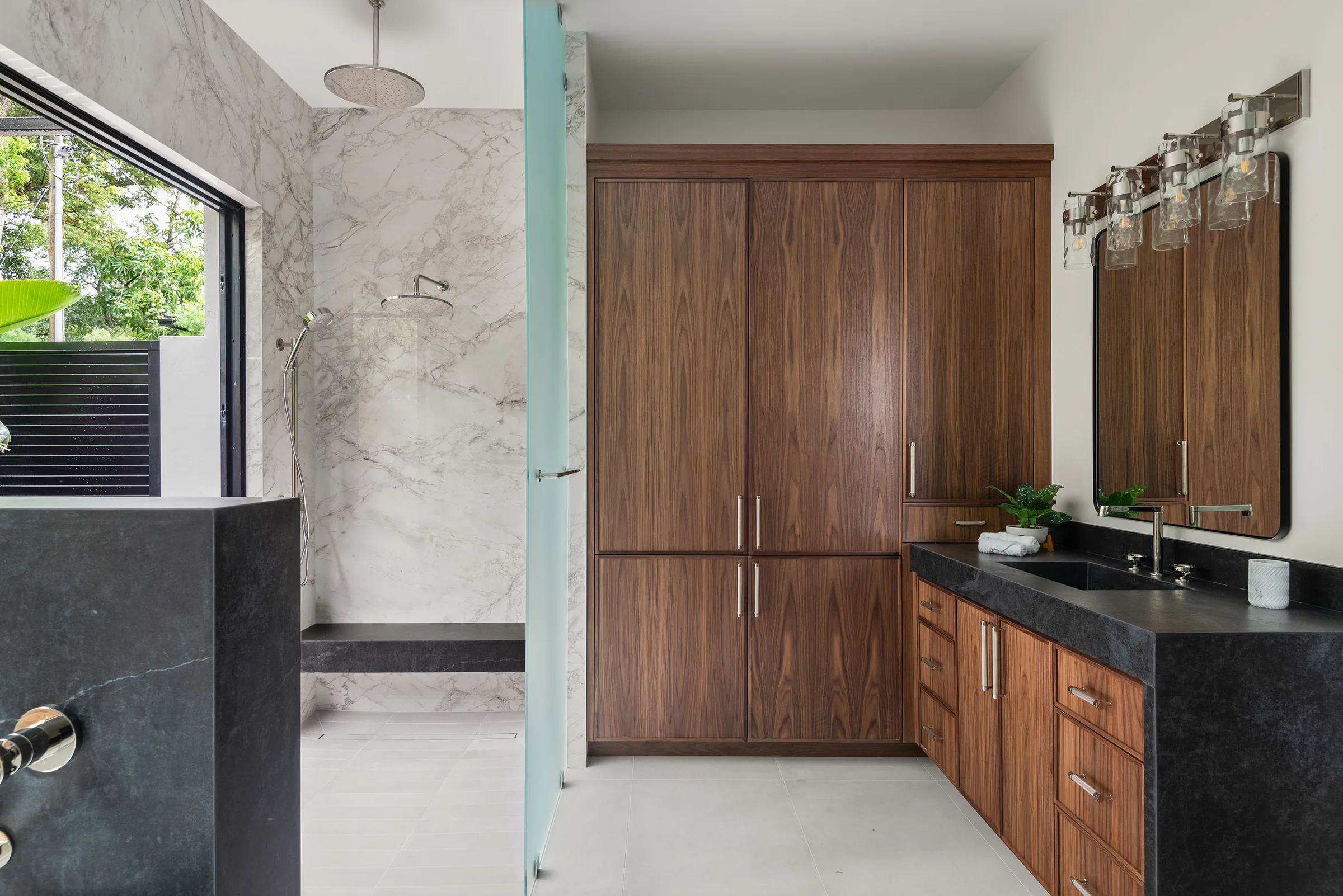 Dark wood vanity with twin mirrors beside the tub. New Hampshire, a custom home by Rare Builders in Orlando.